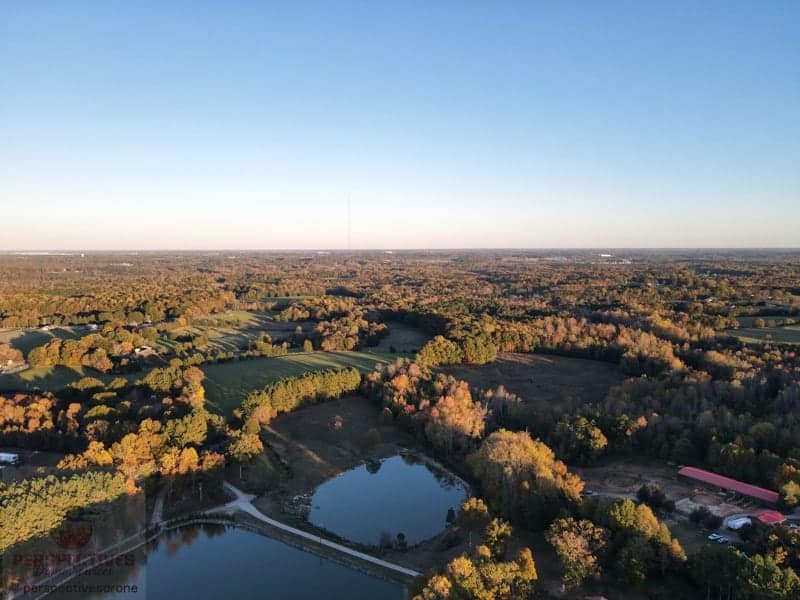 An aerial view of a farm with a pond and trees.