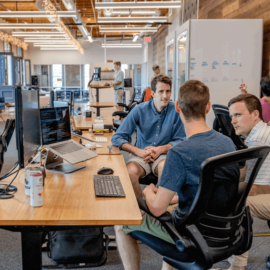 A group of people sitting at desks in an office.