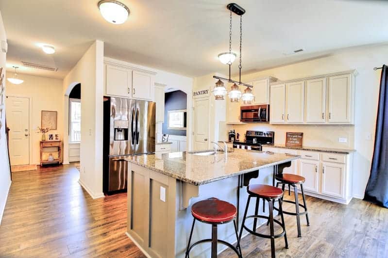 A kitchen with hardwood floors and a bar stools.