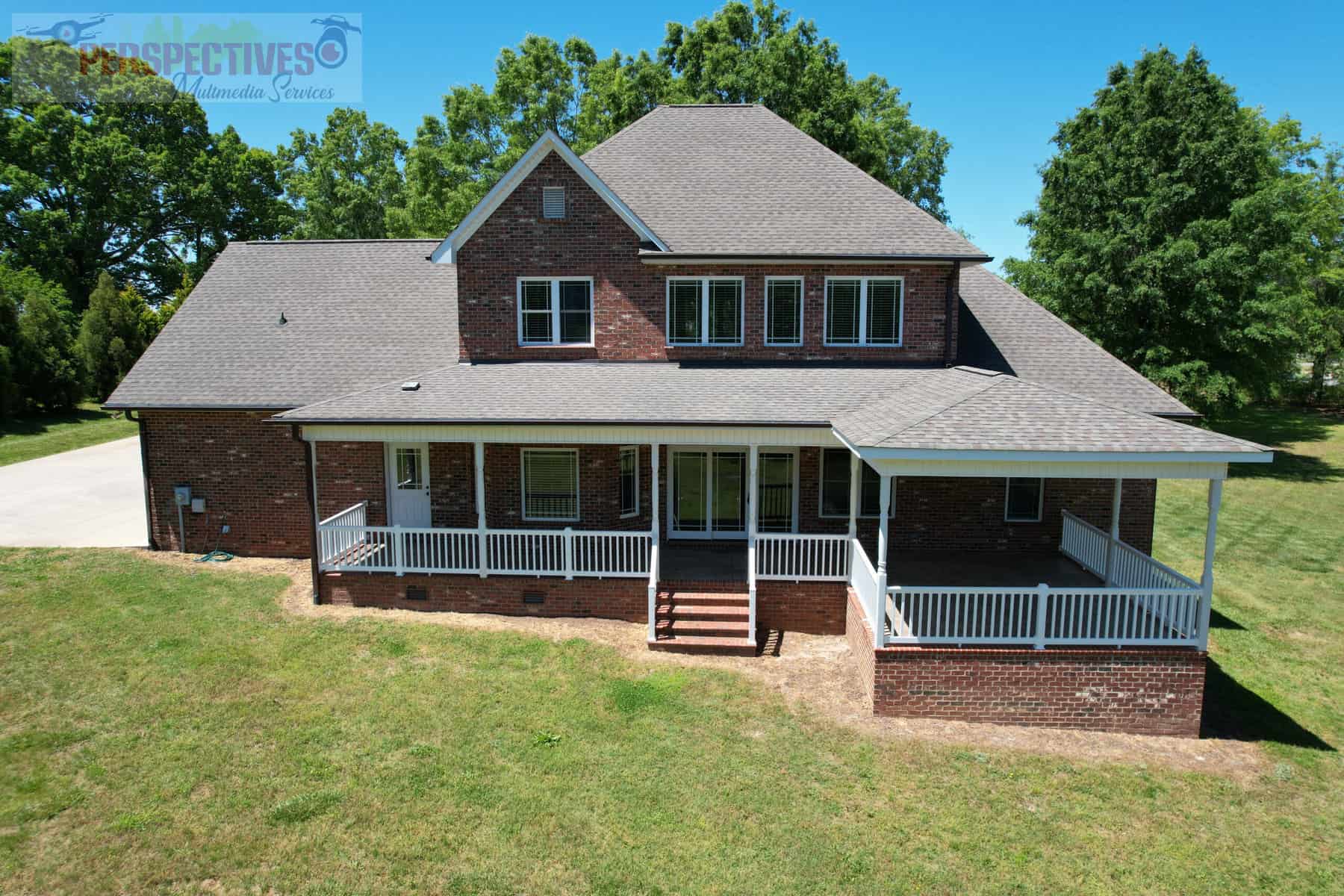 A large brick house with a lawn and trees in the background.