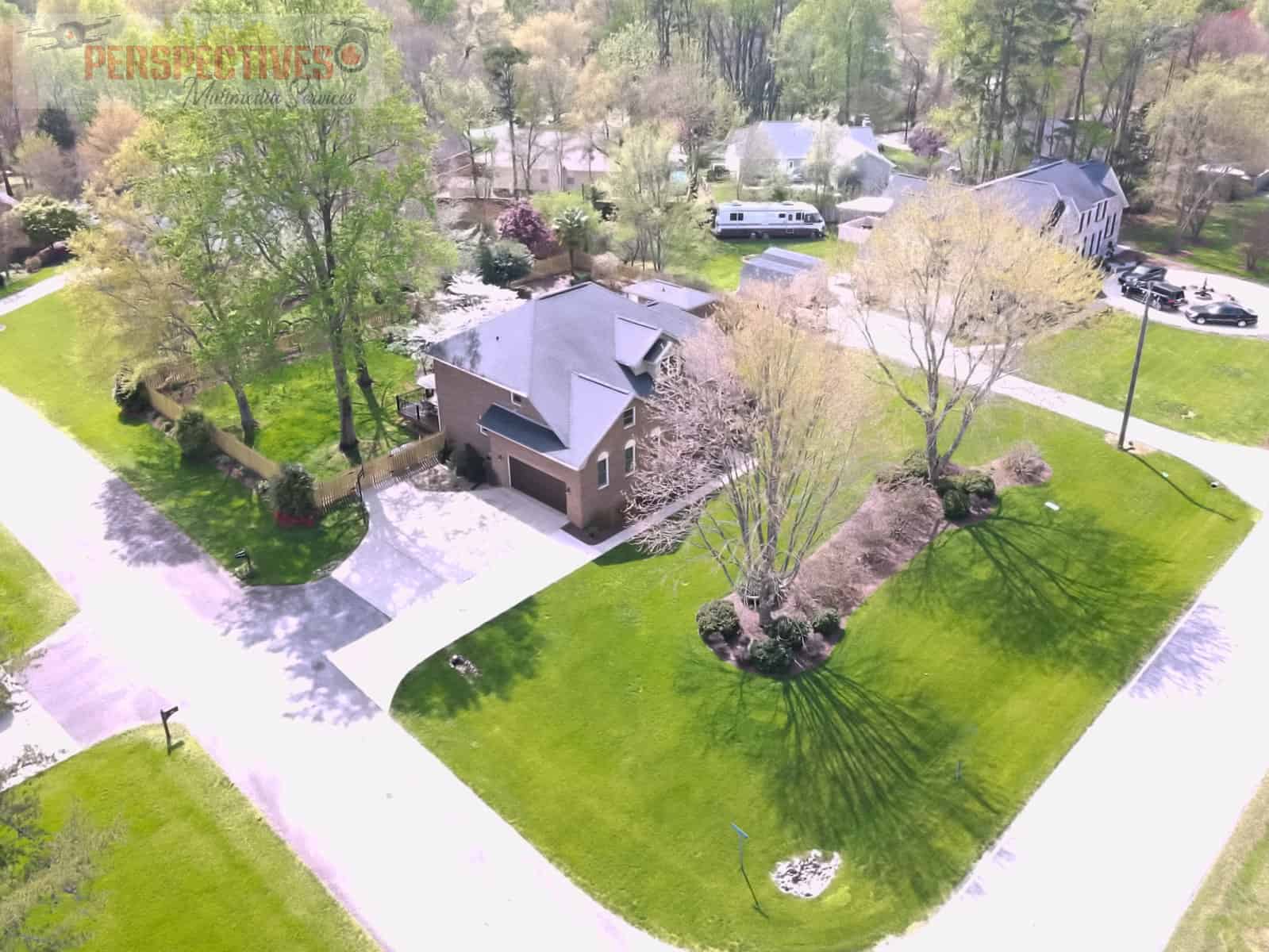 A large green lawn with trees and houses.