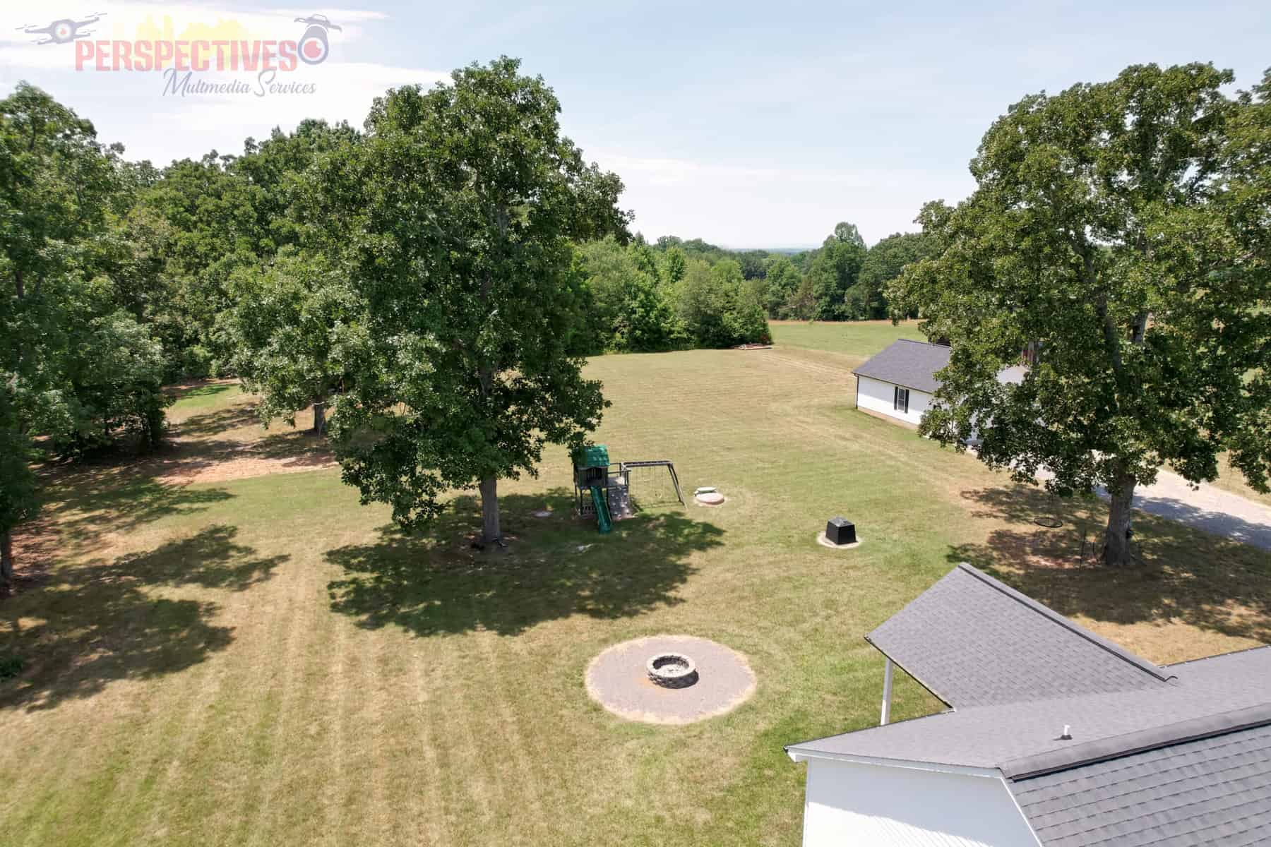 A large grassy area with trees and a playground.