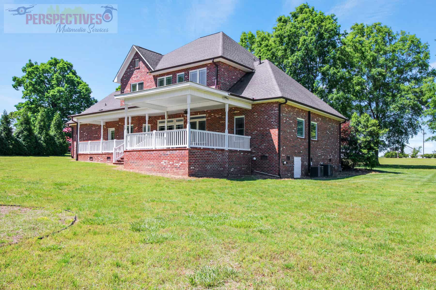 A brick home in the middle of a grassy field.