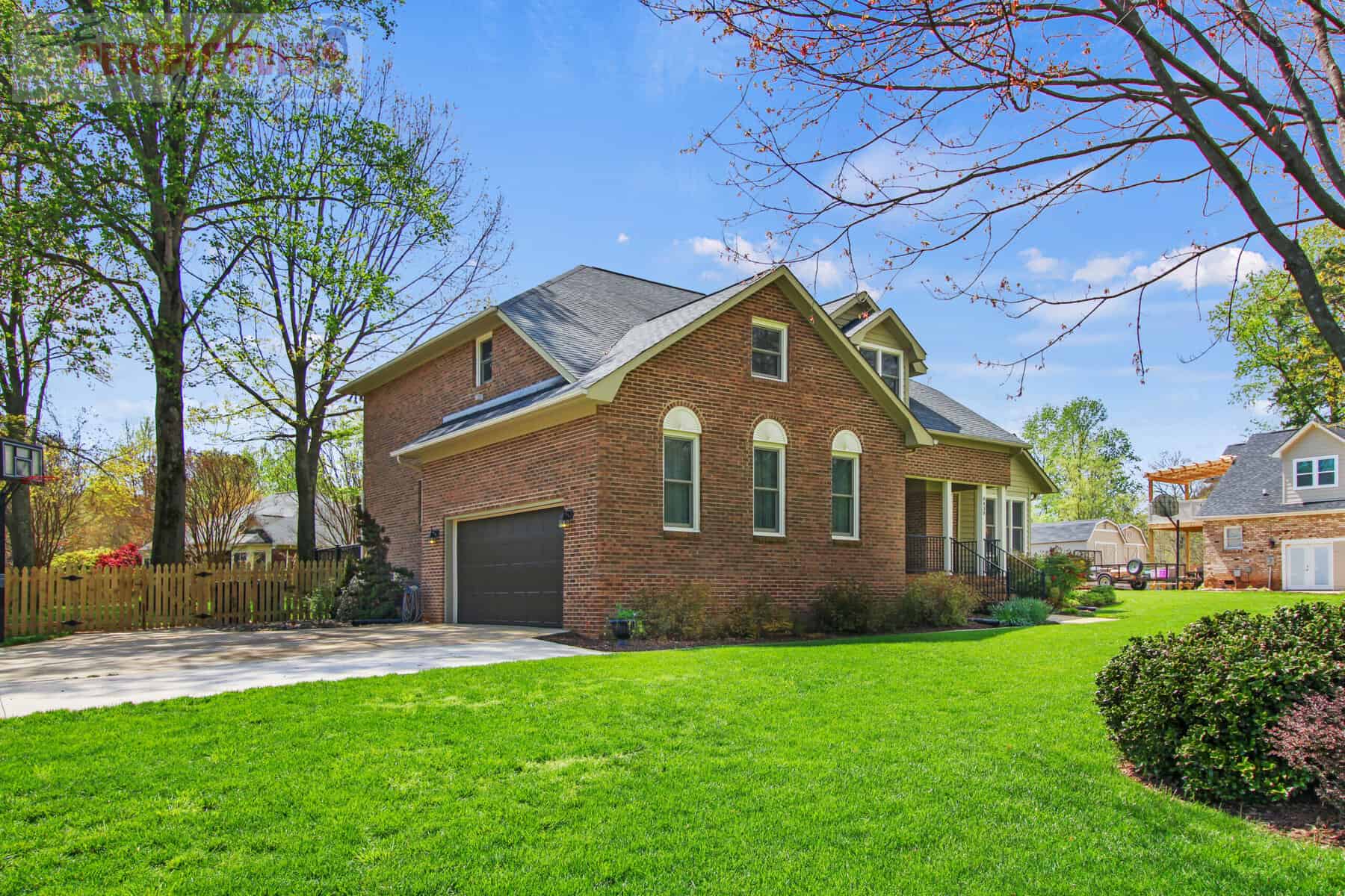 A brick home with green grass and trees.