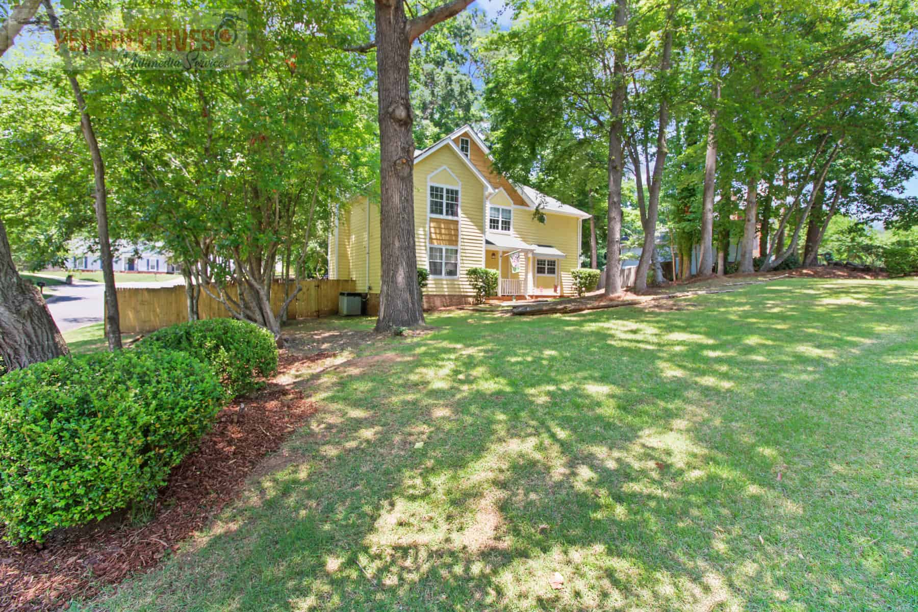 A yellow house in a wooded area with trees.