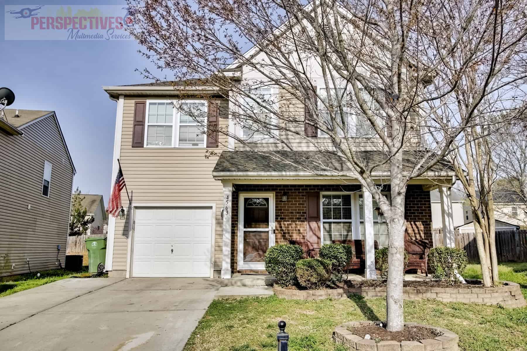 A two story home with a garage in the front yard.