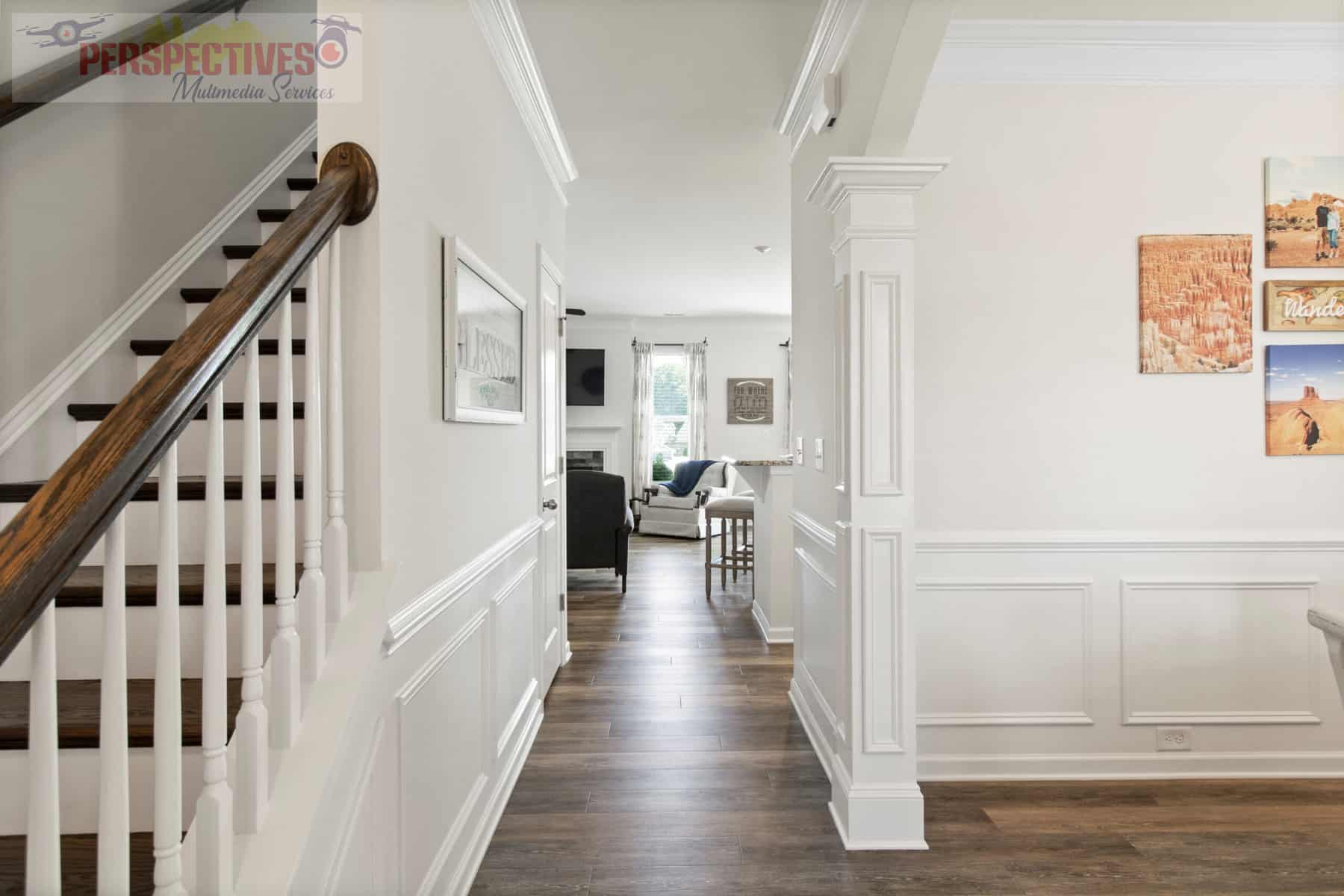 A hallway with hardwood floors and a staircase.