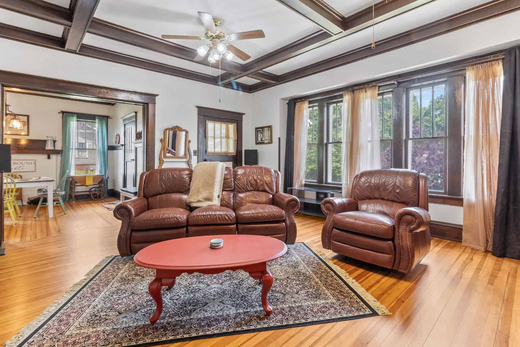 A living room with hardwood floors and brown leather furniture.