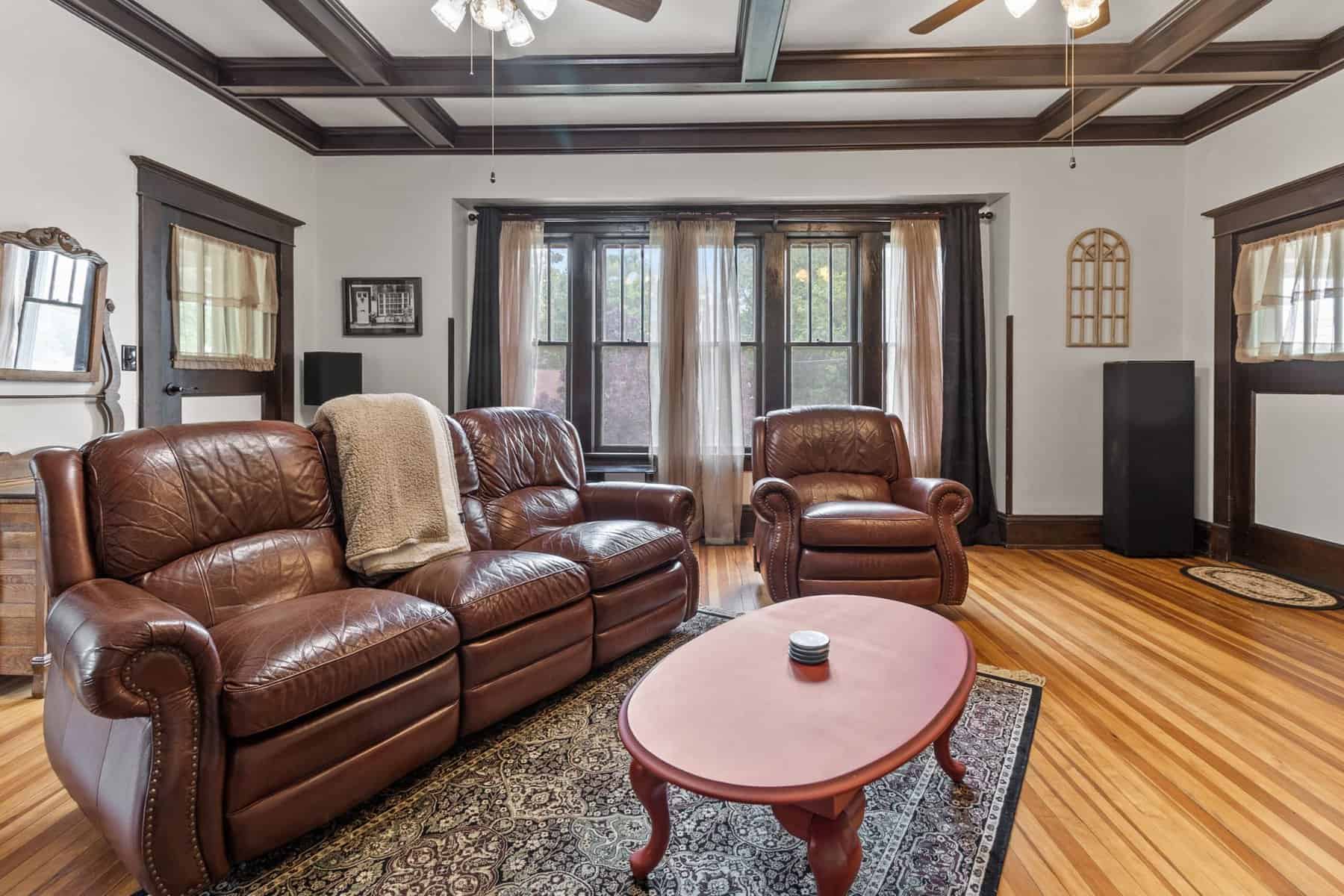 A living room with brown leather furniture and a ceiling fan.