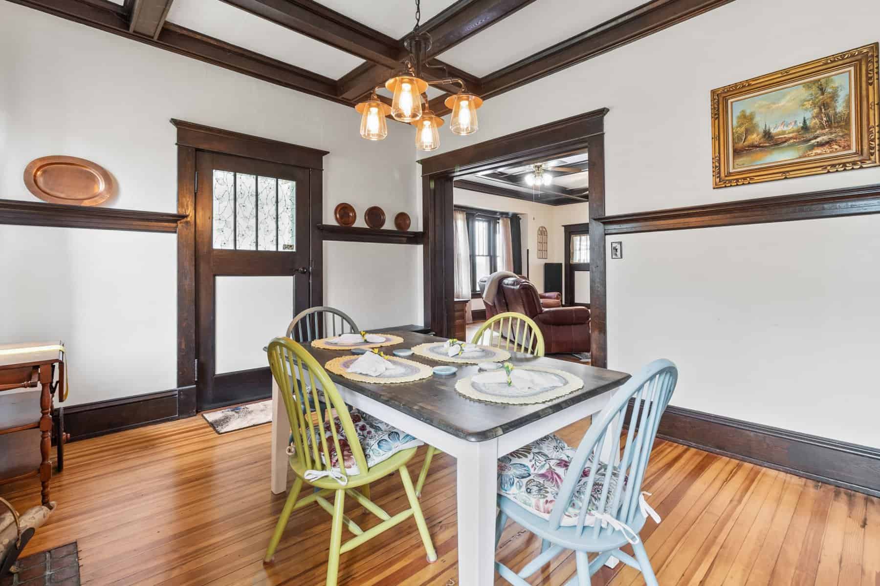 A dining room with hardwood floors and wood paneling.