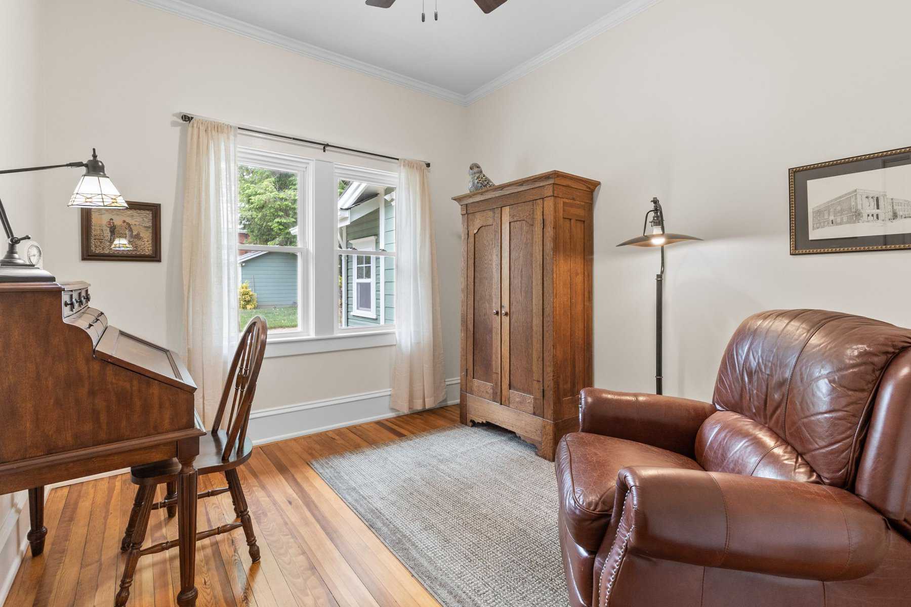 A room with a brown leather chair and a fan.