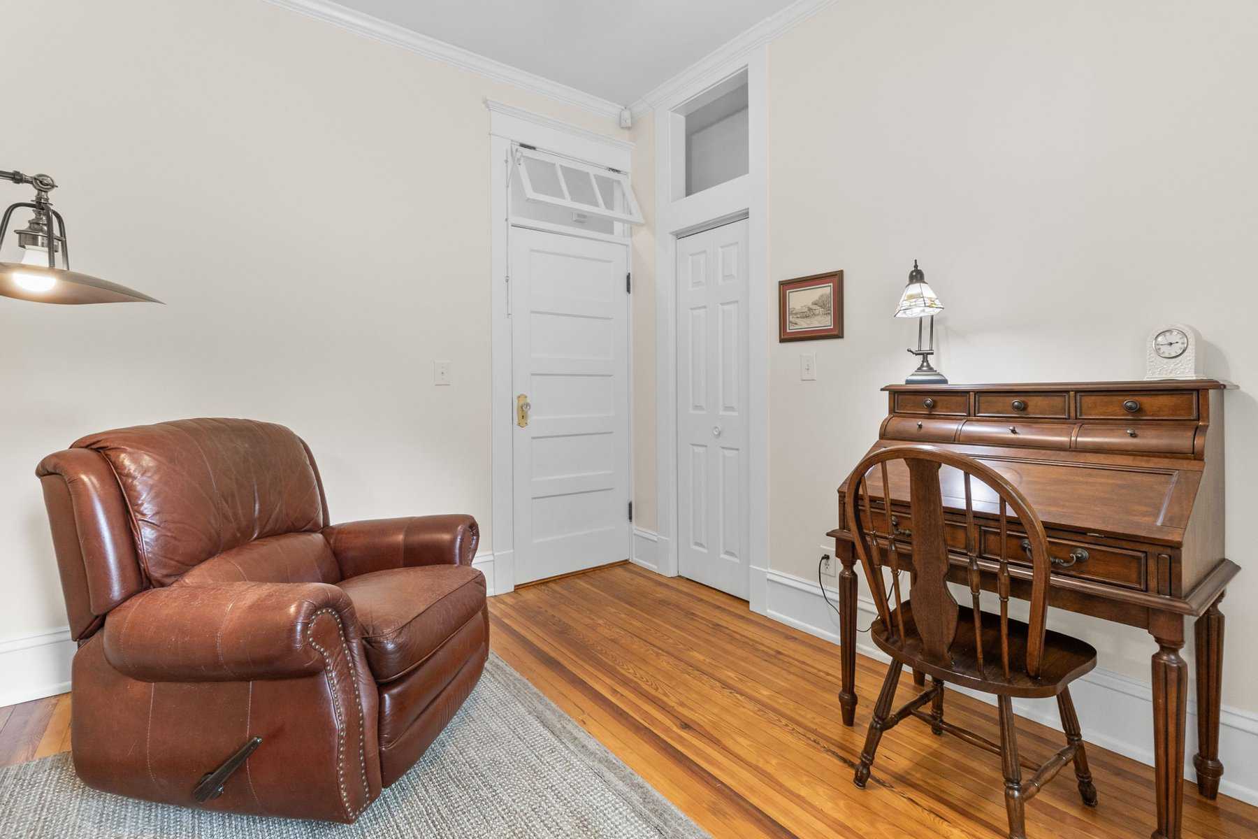 A room with a brown leather chair and a desk.