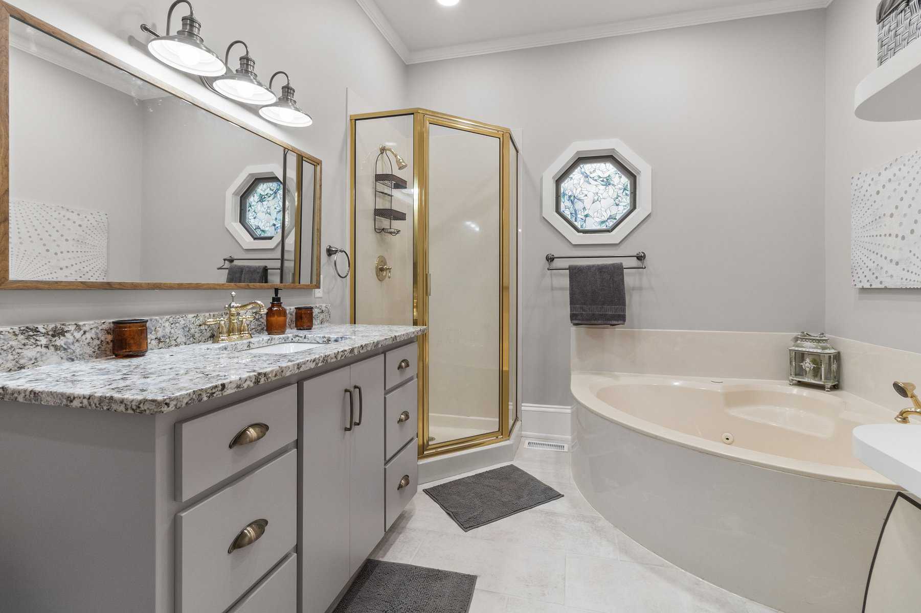 A bathroom with a tub, sink and mirror.