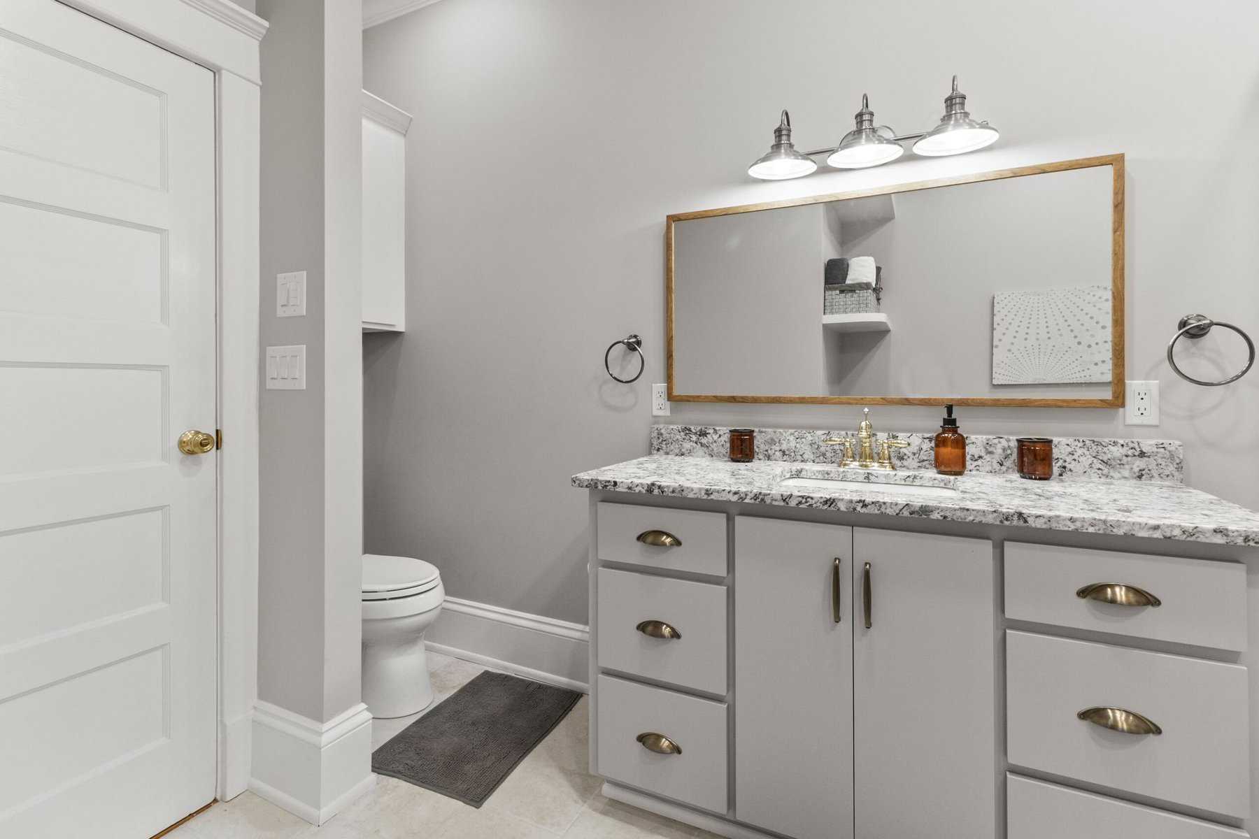 A bathroom with gray cabinets and a mirror.