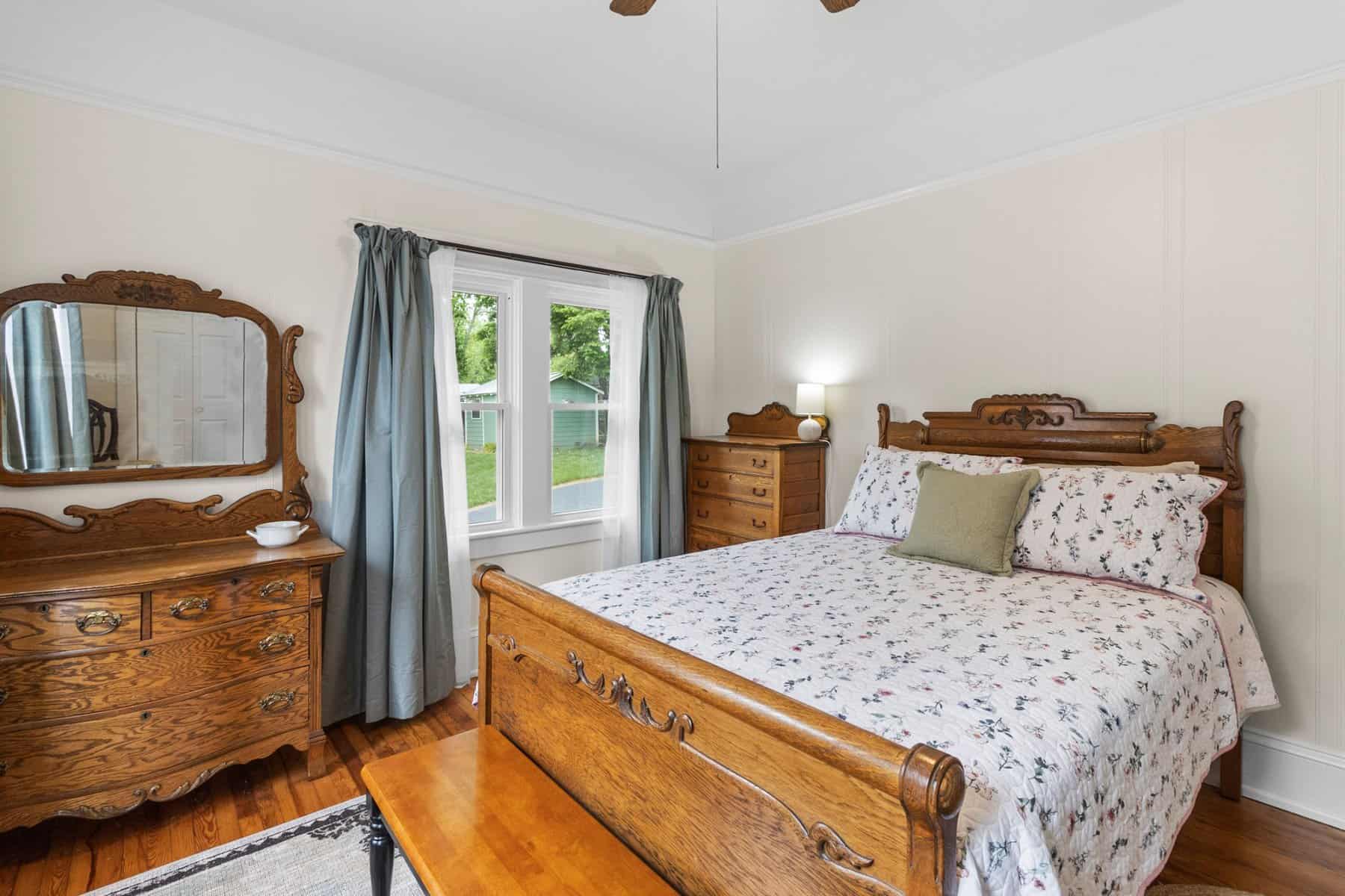 A bedroom with wooden furniture and a ceiling fan.