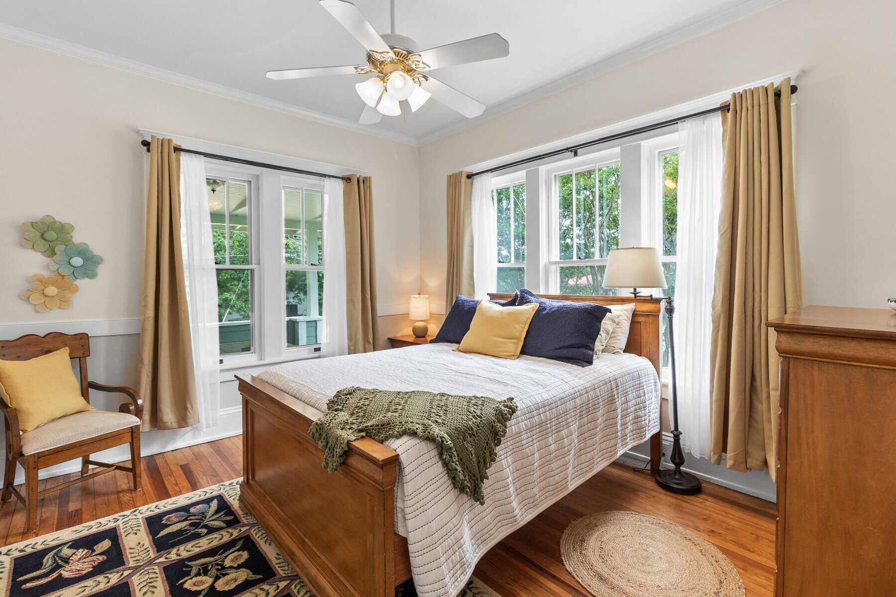 A bedroom with hardwood floors and a ceiling fan.