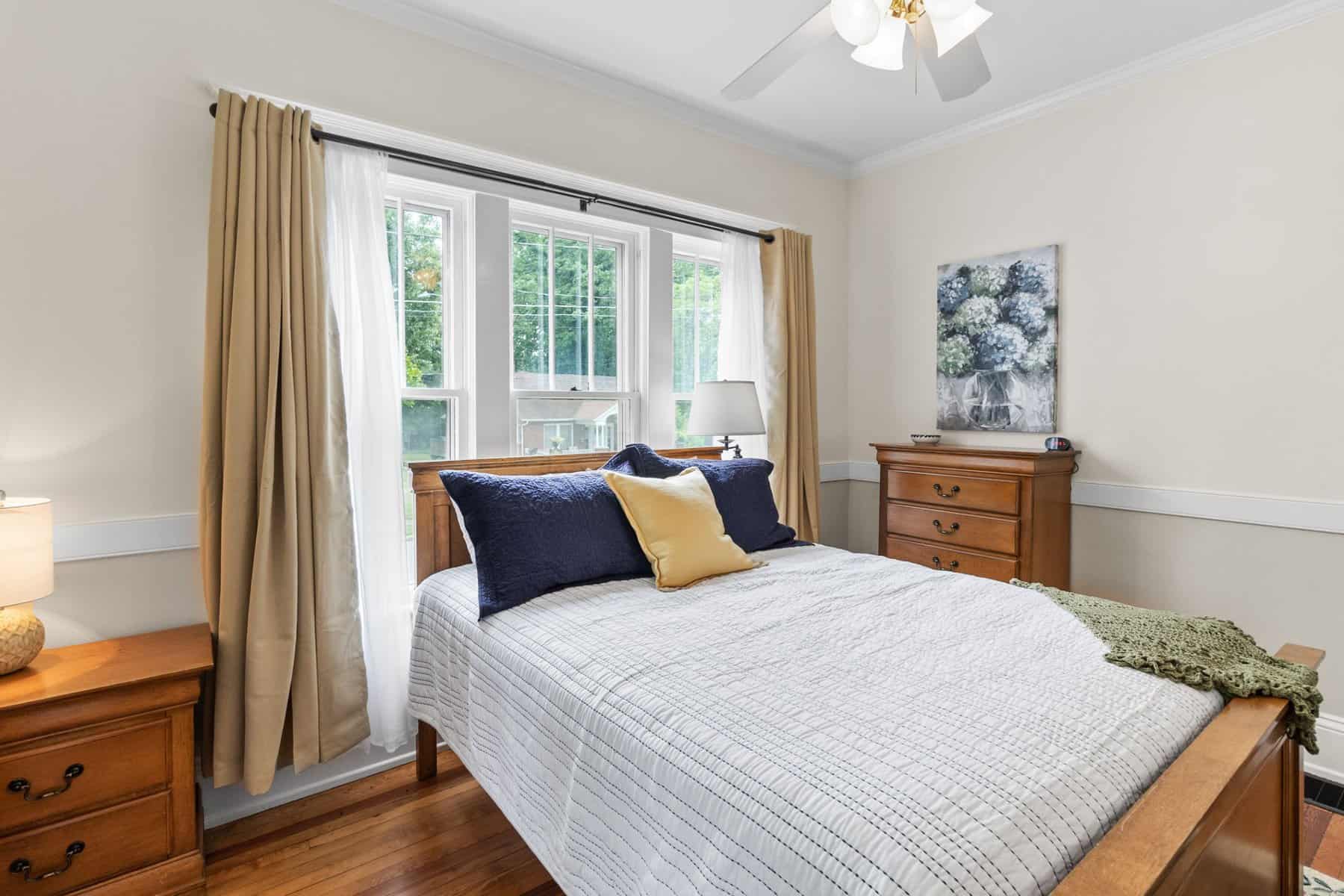 A bedroom with hardwood floors and a ceiling fan.