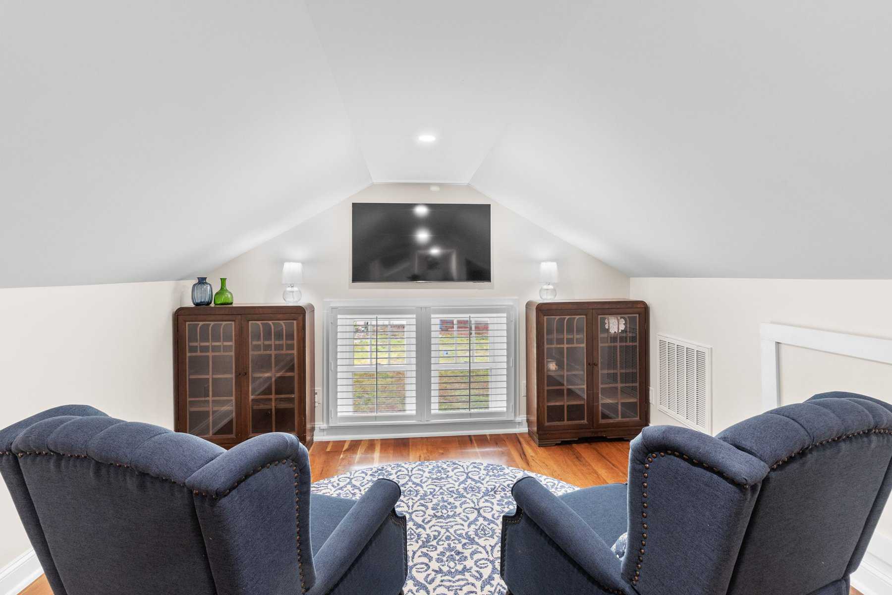 A living room with blue chairs and a tv.