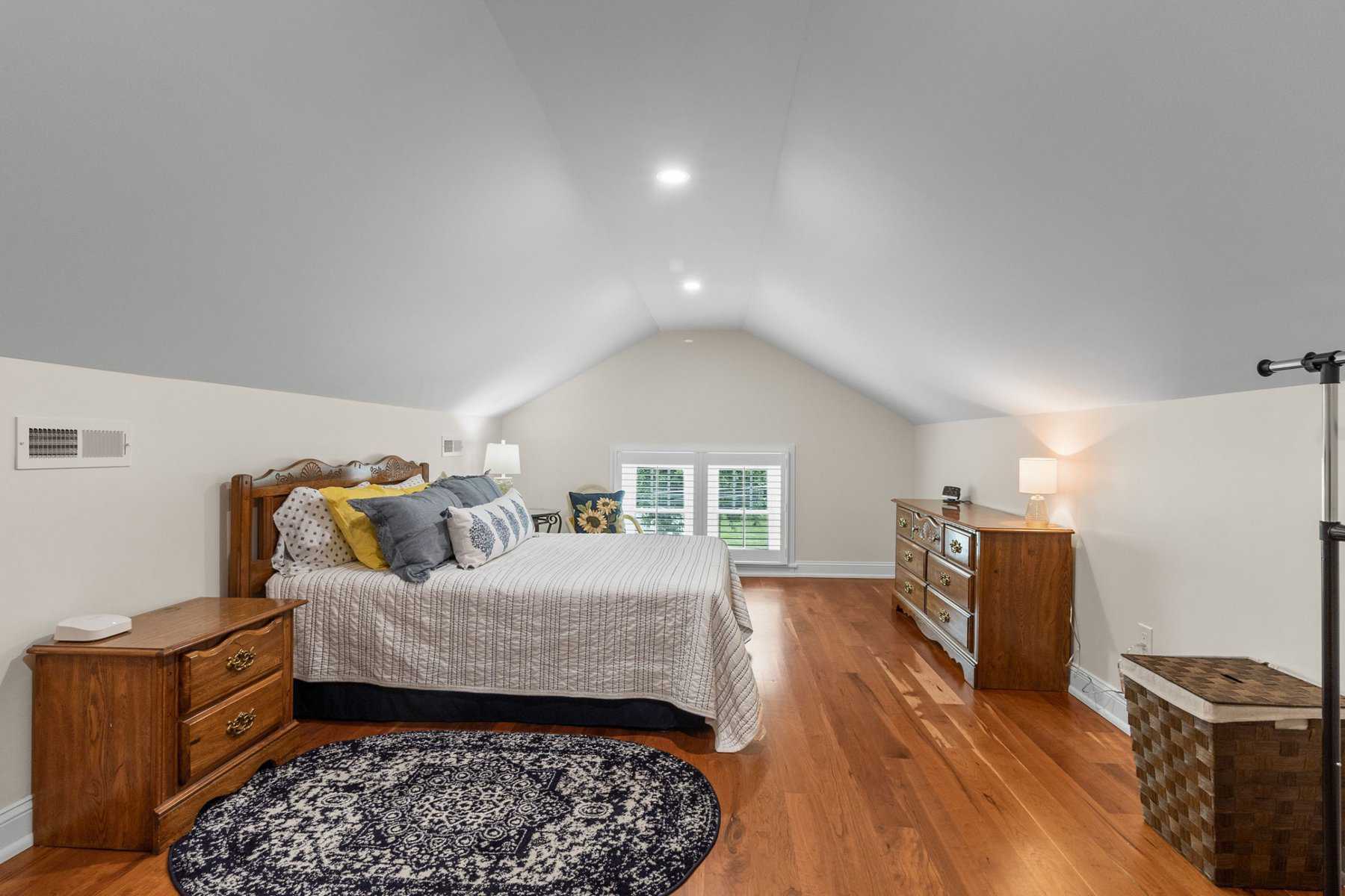 A bedroom with hardwood floors and a bed.