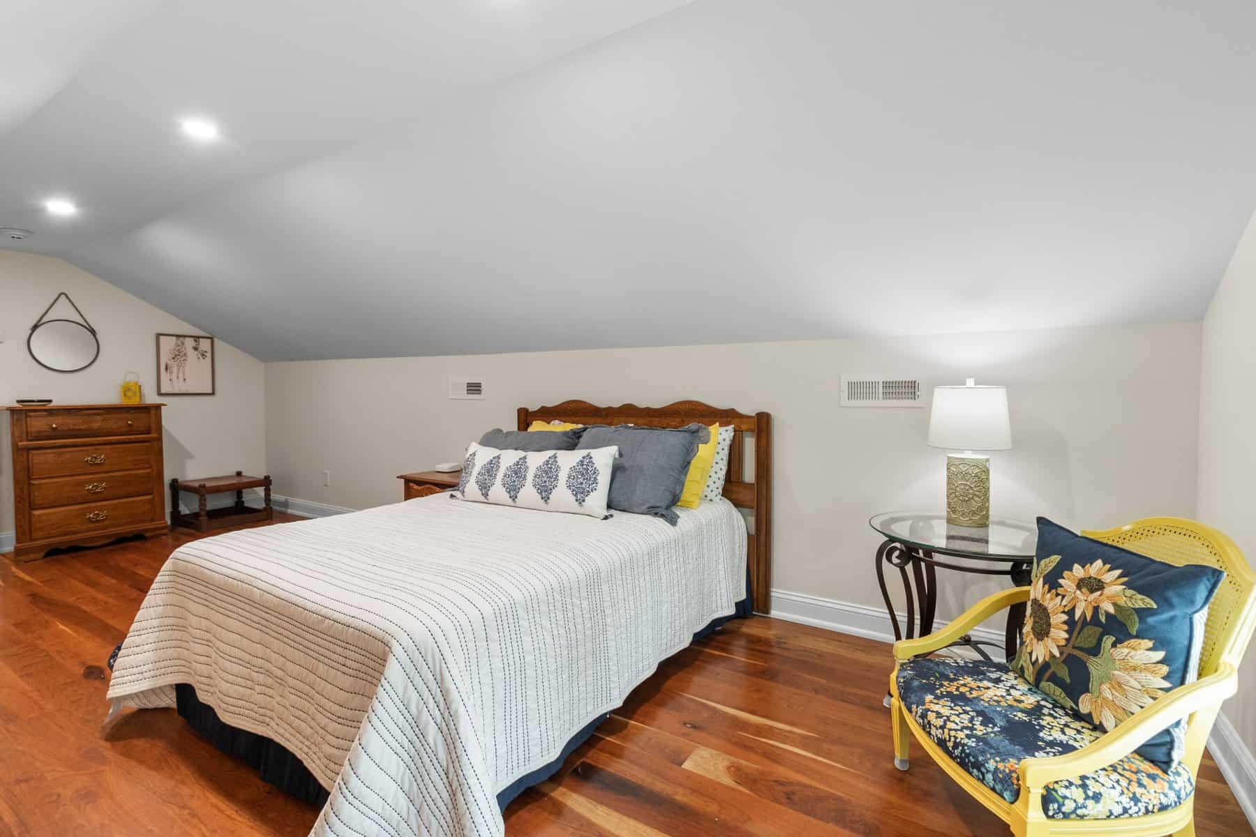 A bedroom with hardwood floors and a bed.