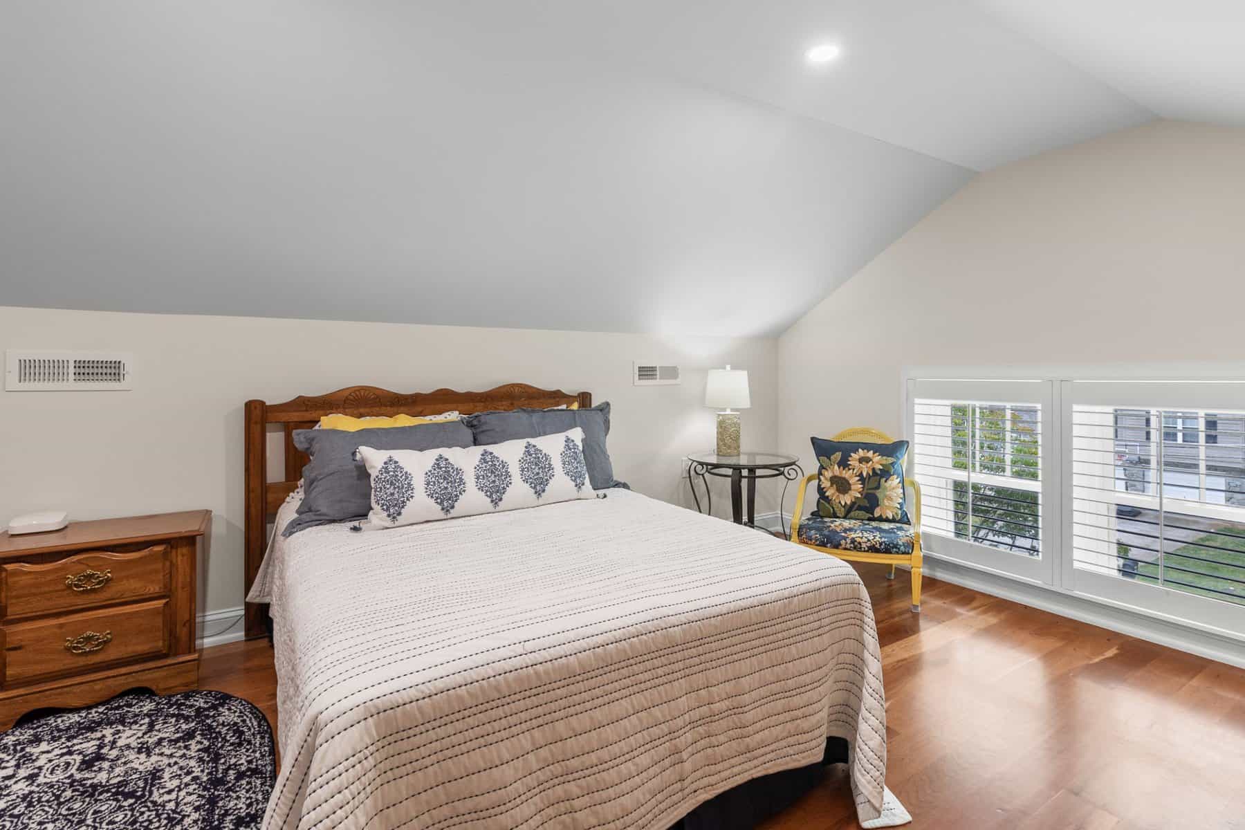 A bedroom with hardwood floors and an attic.