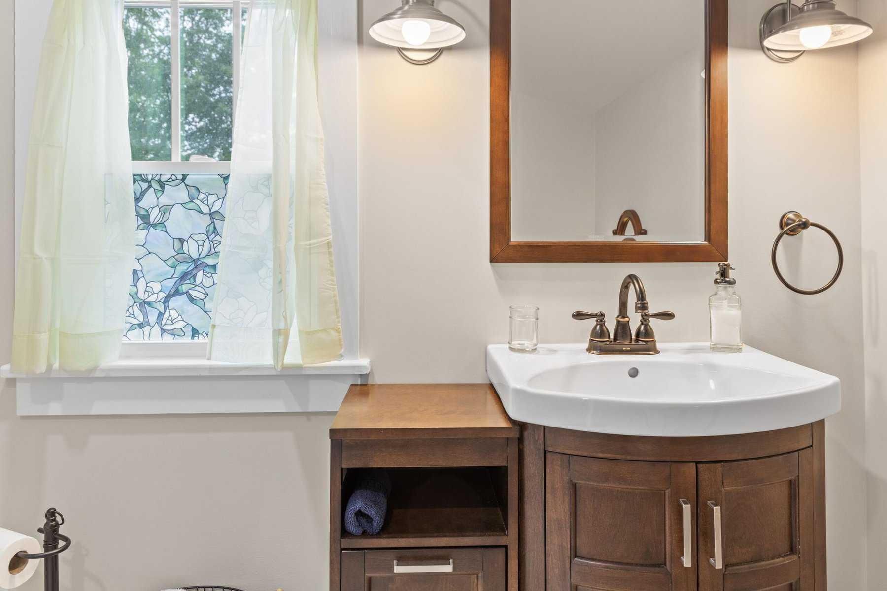 A bathroom with a sink, toilet and window.