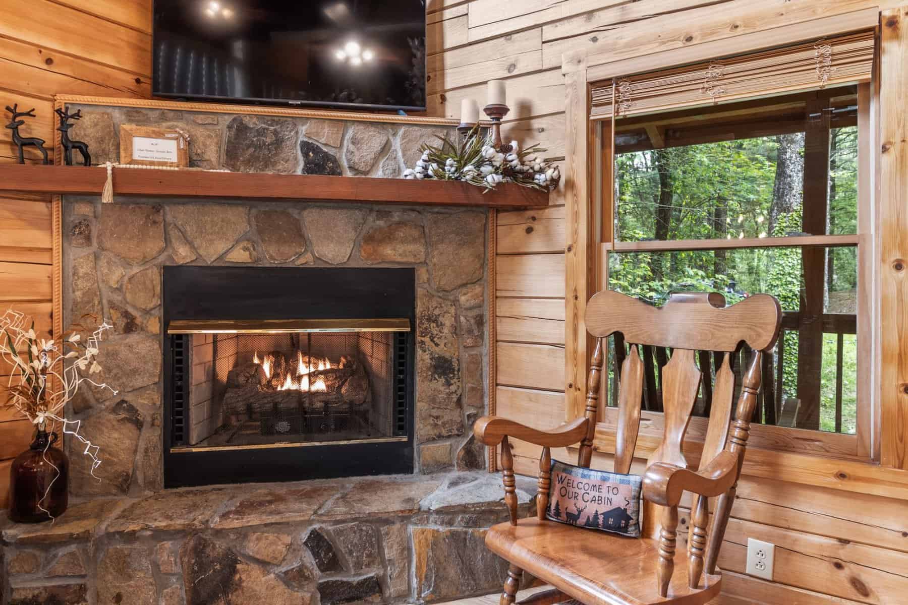 A rocking chair in front of a fireplace in a cabin.