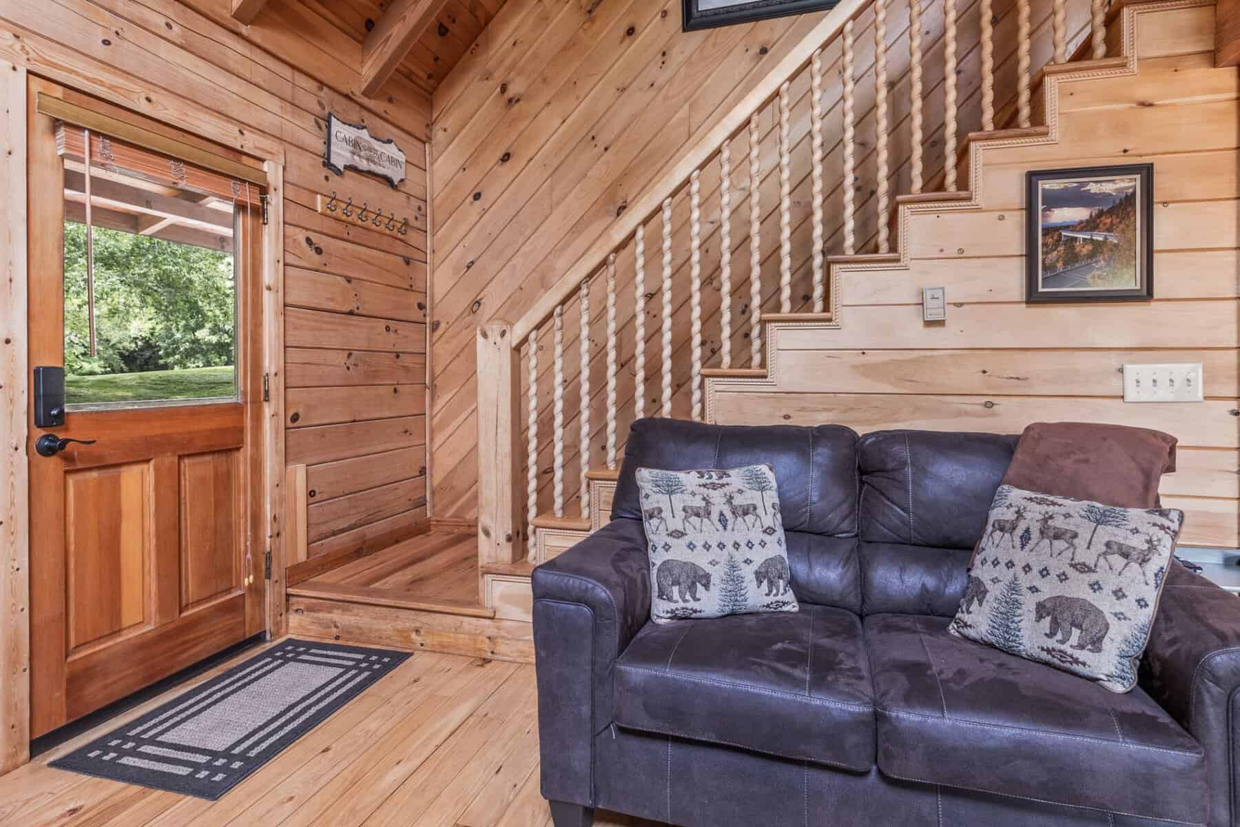 A living room in a log cabin with a couch and stairs.