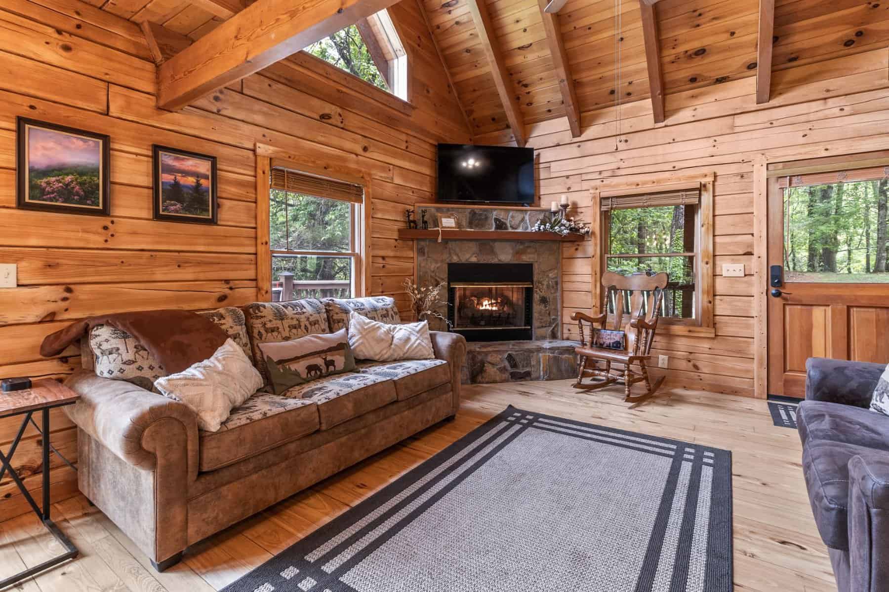 A living room in a log cabin with a fireplace.