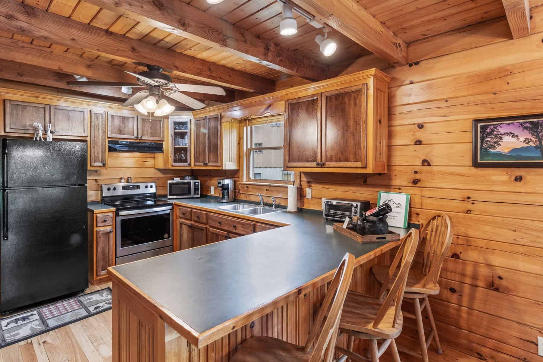 A kitchen in a log cabin with a refrigerator and microwave.