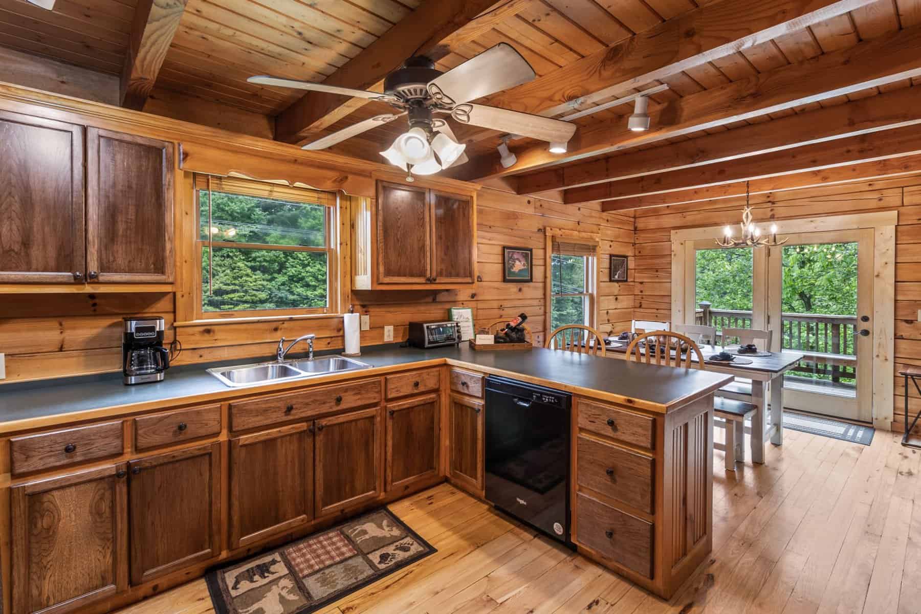 A kitchen in a log cabin with a ceiling fan.