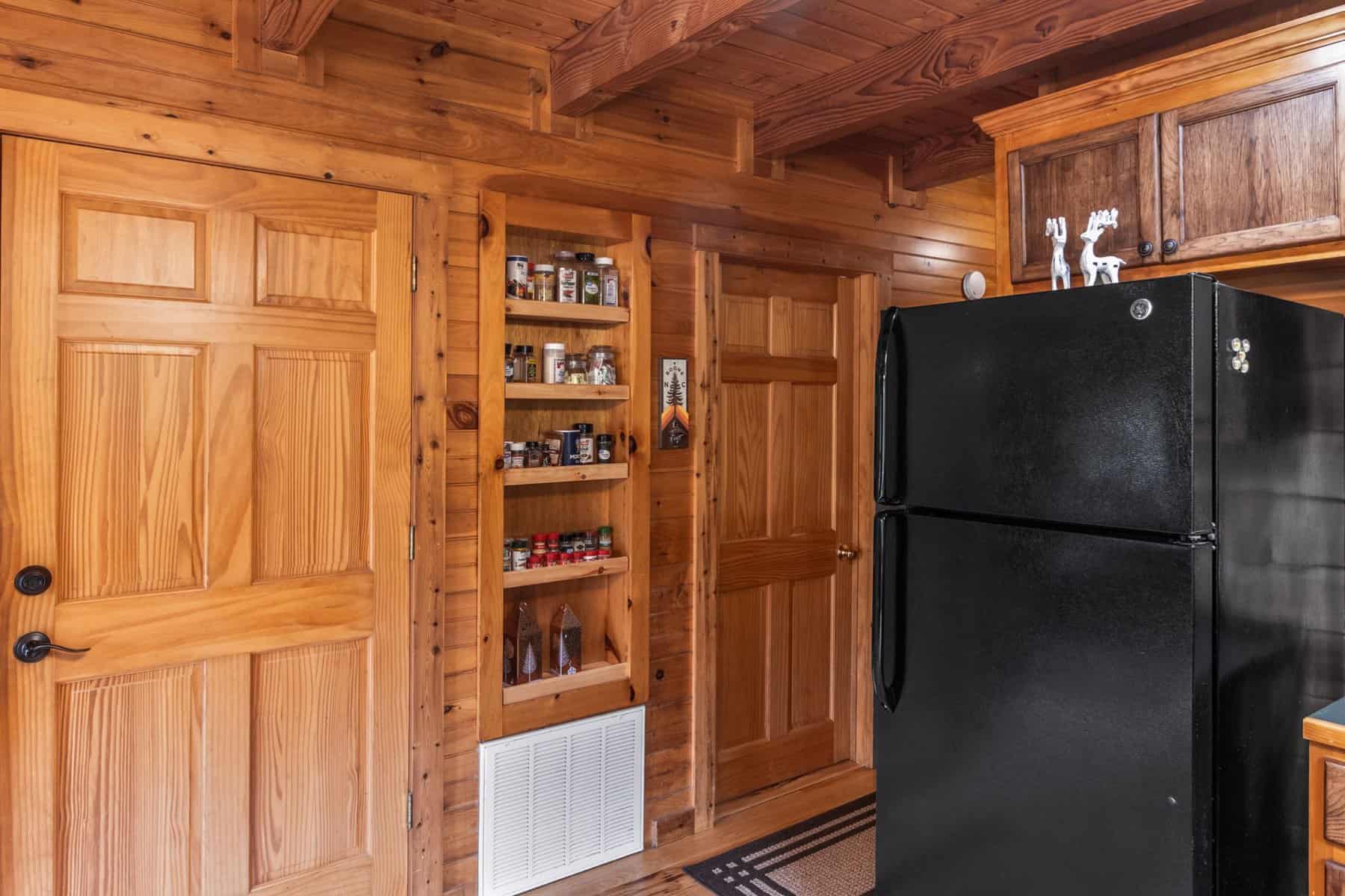 A kitchen in a log cabin with a black refrigerator.