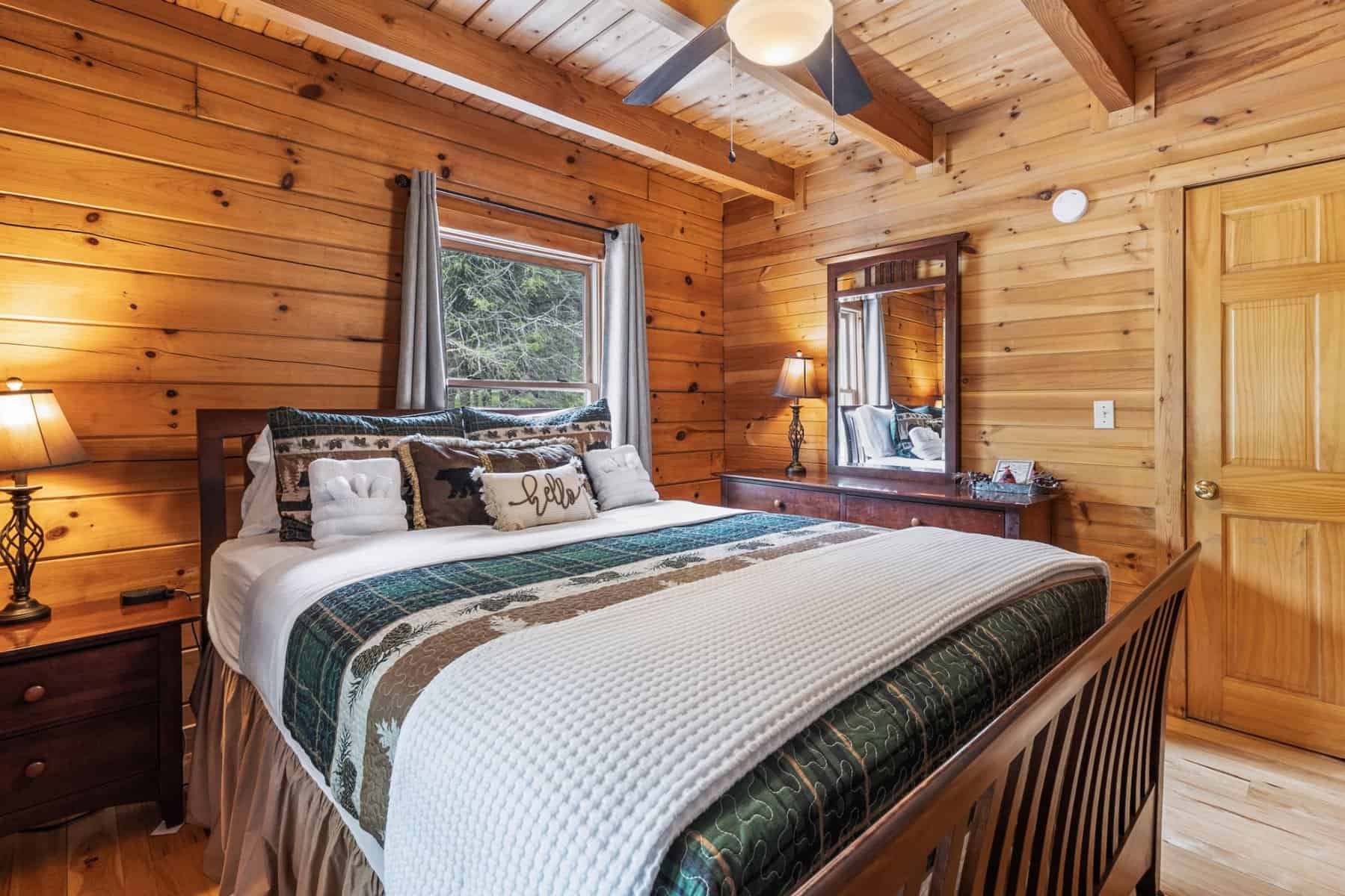 A bedroom in a log cabin with a bed and a ceiling fan.