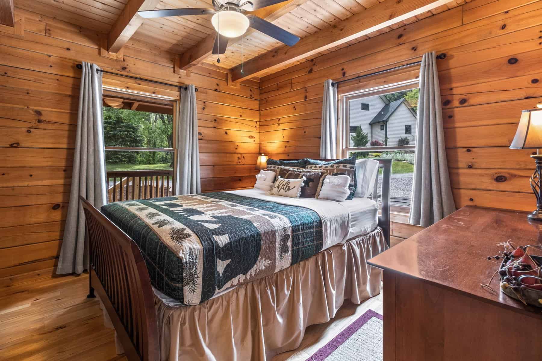 A bedroom in a log cabin with a bed and a ceiling fan.