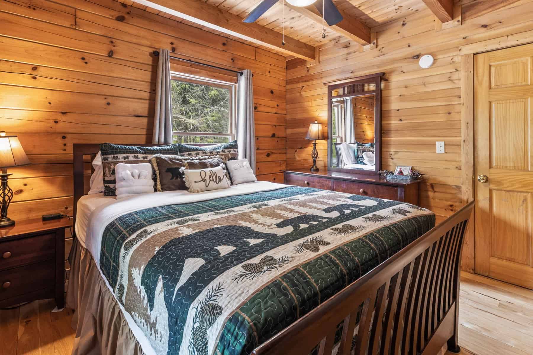 A bedroom in a log cabin with a bed and a ceiling fan.