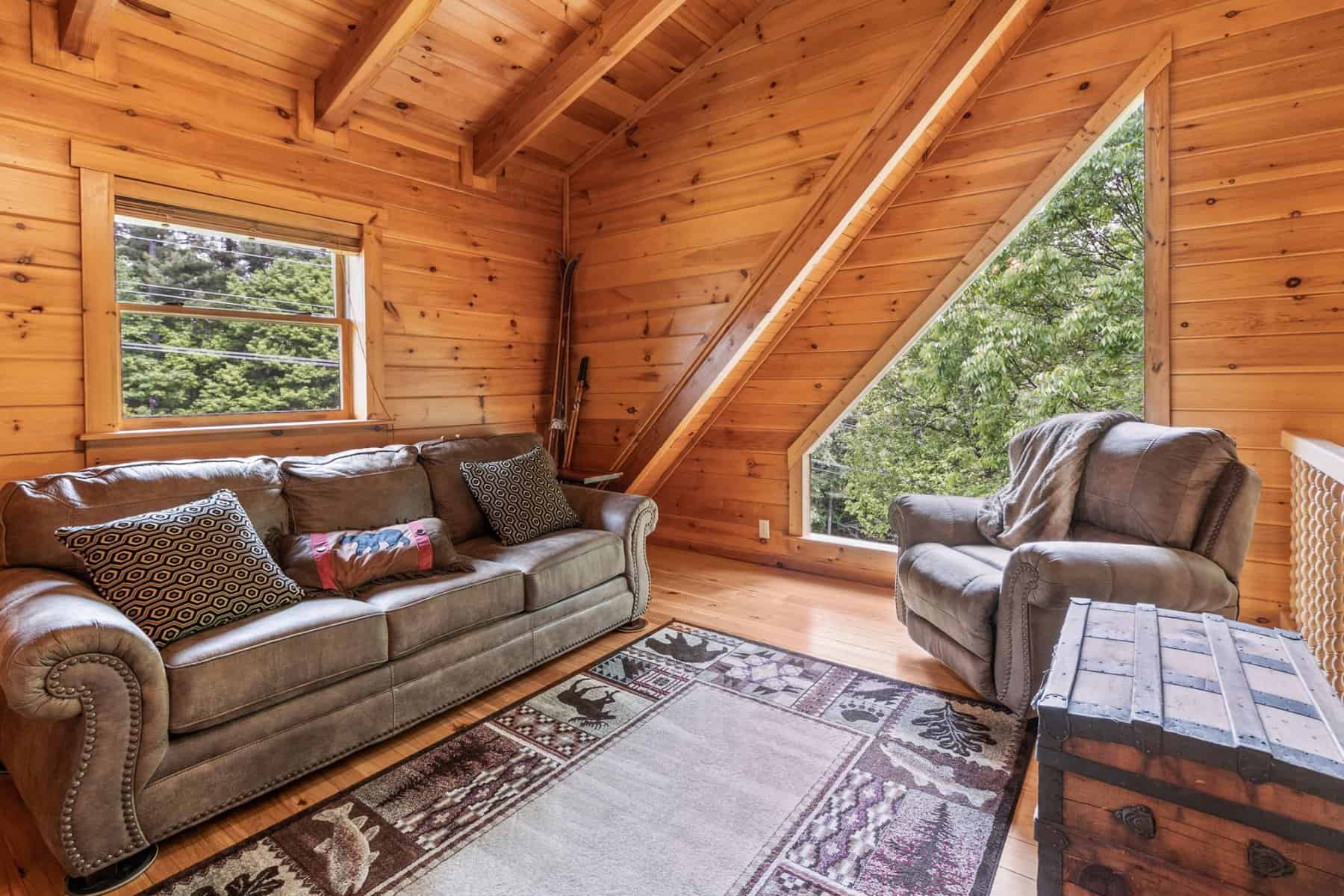 A living room in a log cabin with a couch and tv.