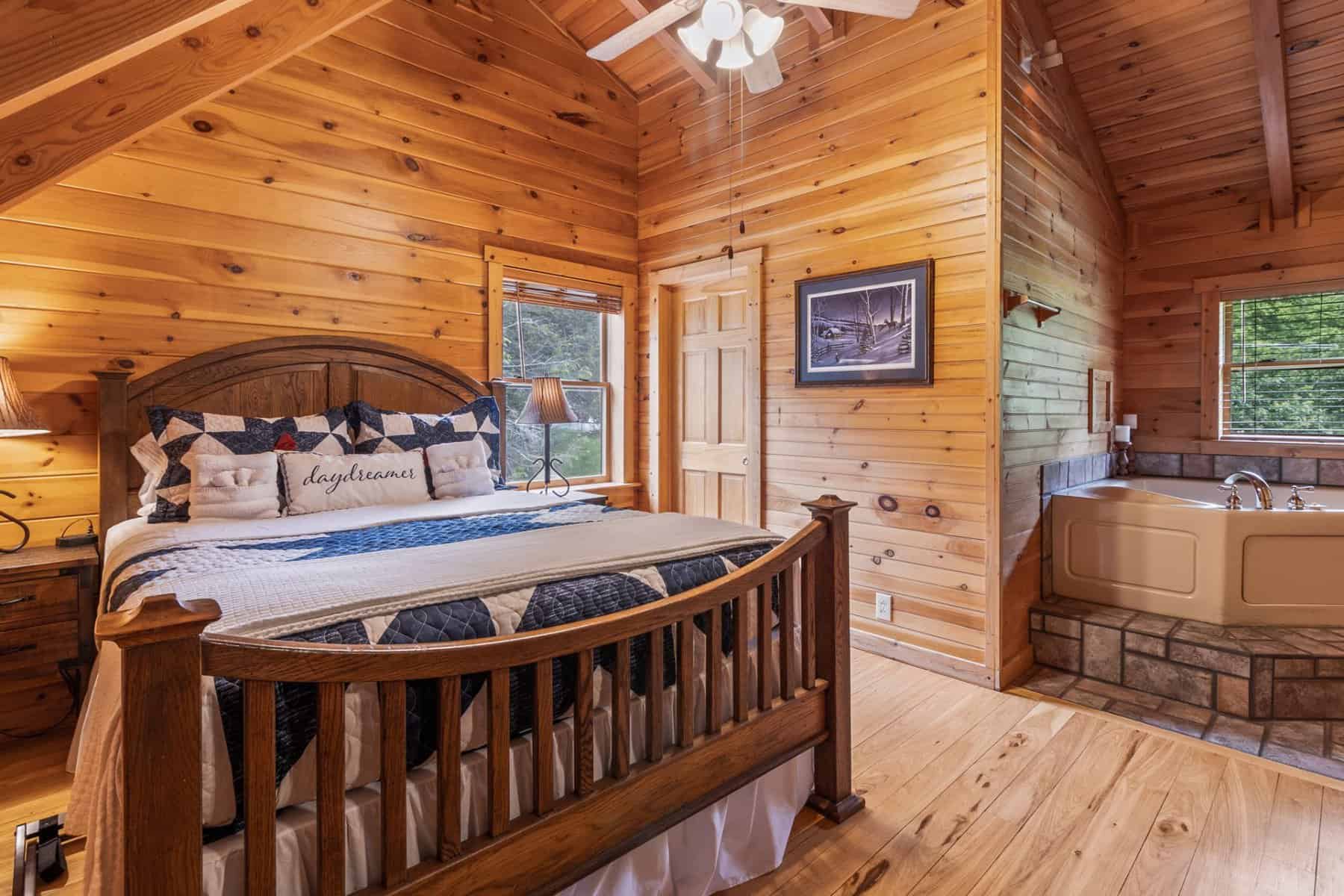 A bedroom in a log cabin with a jacuzzi tub.