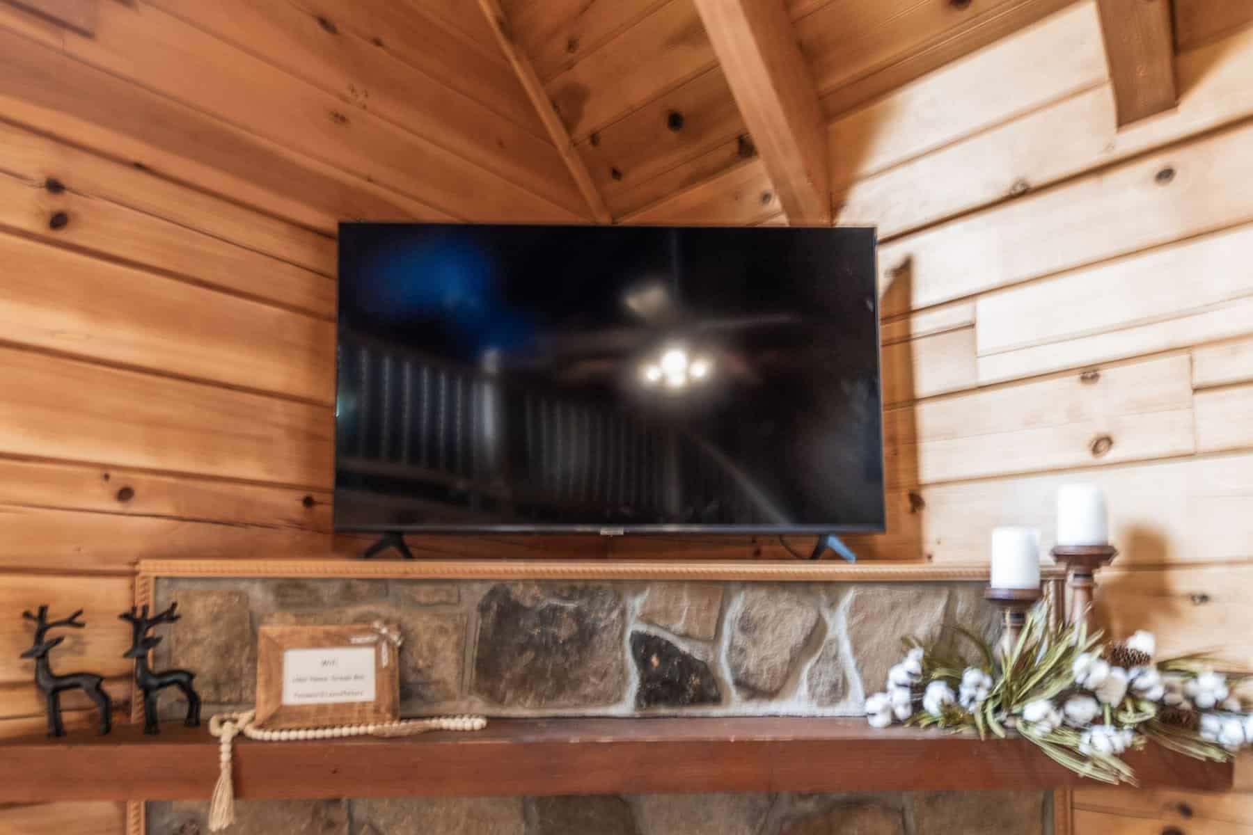 A fireplace in a log cabin with a tv above it.