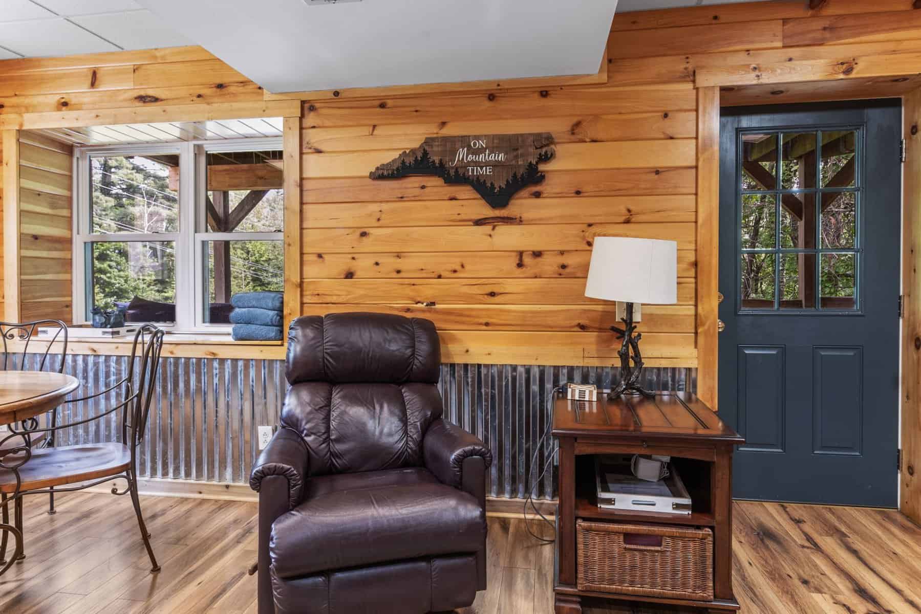 A living room in a log cabin with a table and chairs.