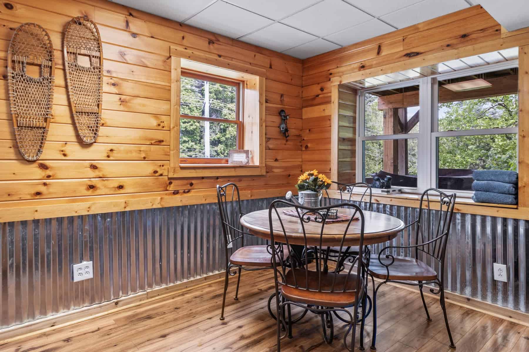 A dining room in a log cabin with a table and chairs.