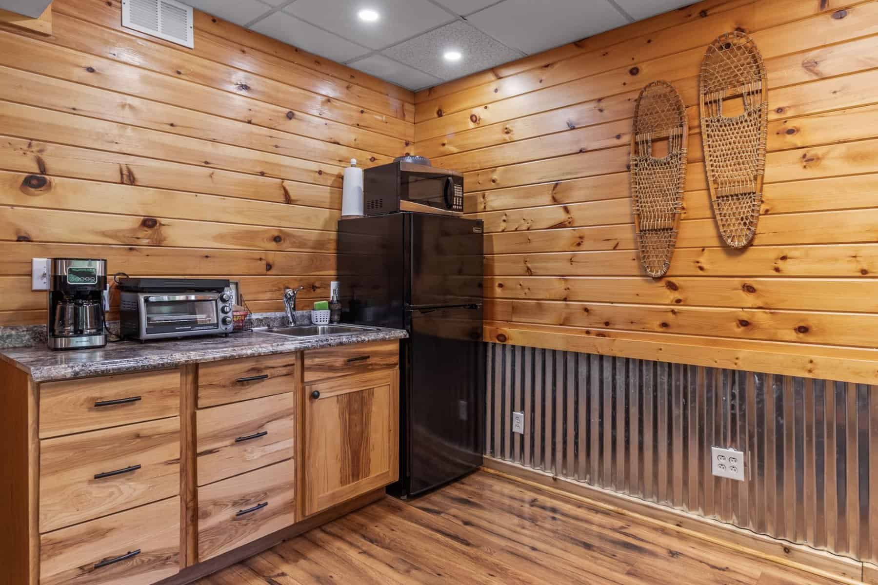 A kitchen in a log cabin with wood paneling.