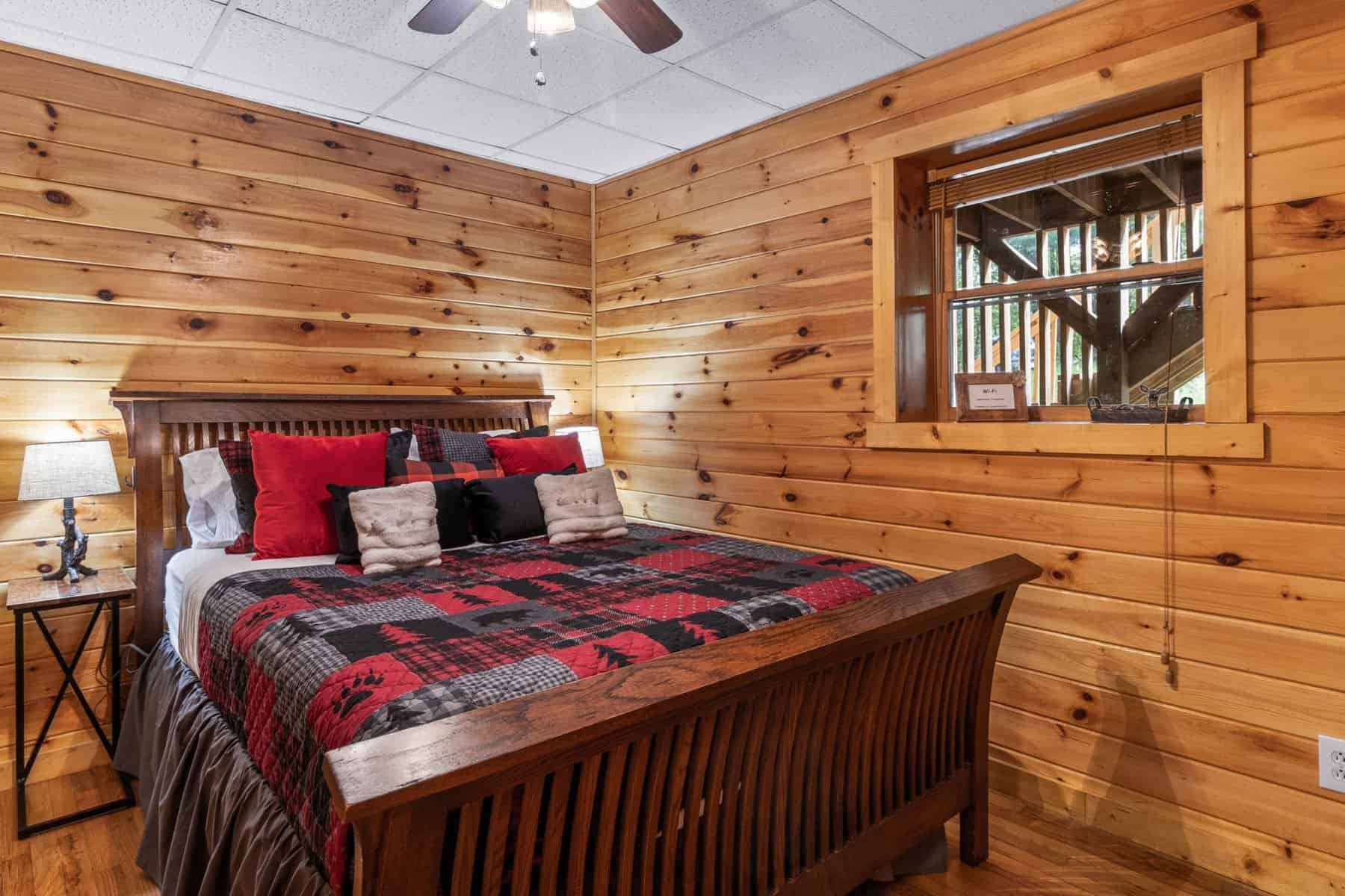 A bedroom in a log cabin with a bed and a ceiling fan.