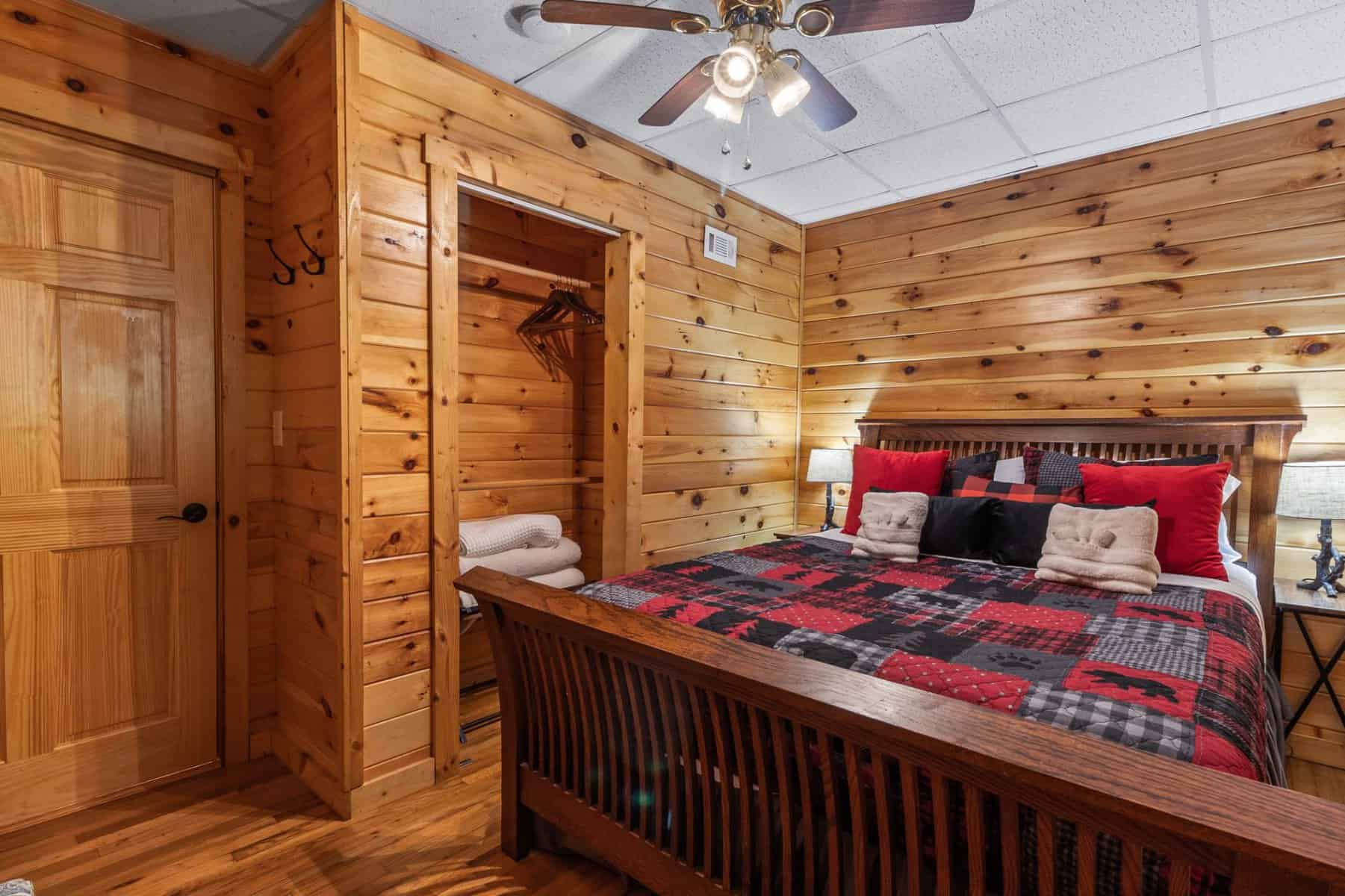 A bedroom in a log cabin with a bed and a ceiling fan.