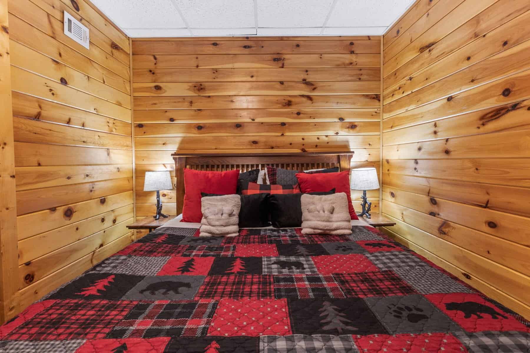 A bed in a cabin with wood paneling.