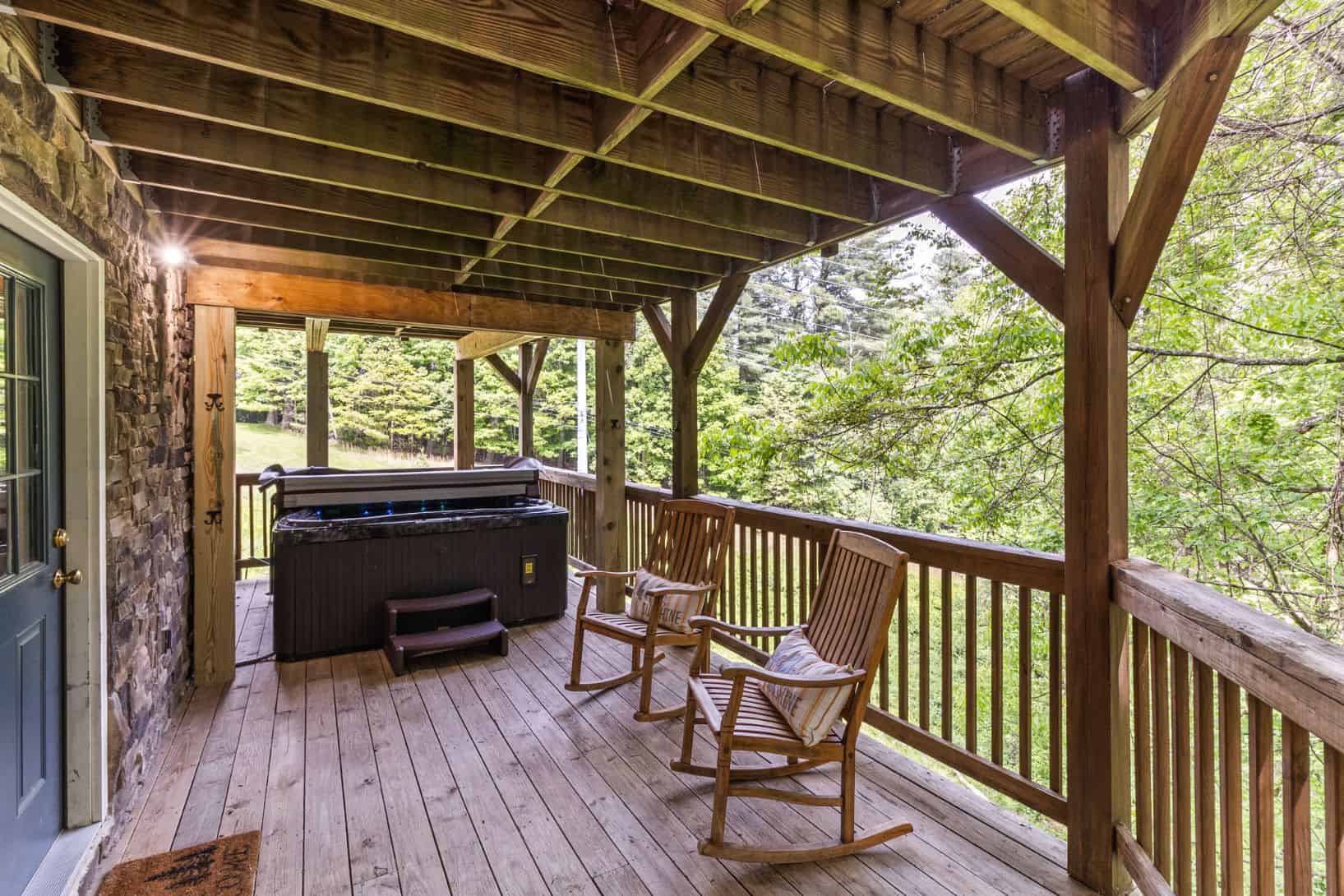 A deck with rocking chairs and a hot tub.