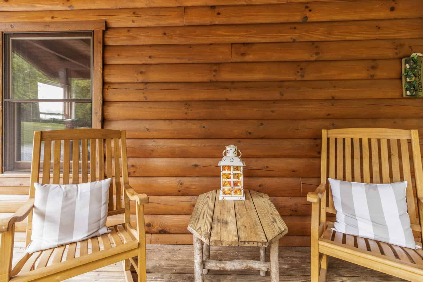 Two wooden rocking chairs on the porch of a log cabin.