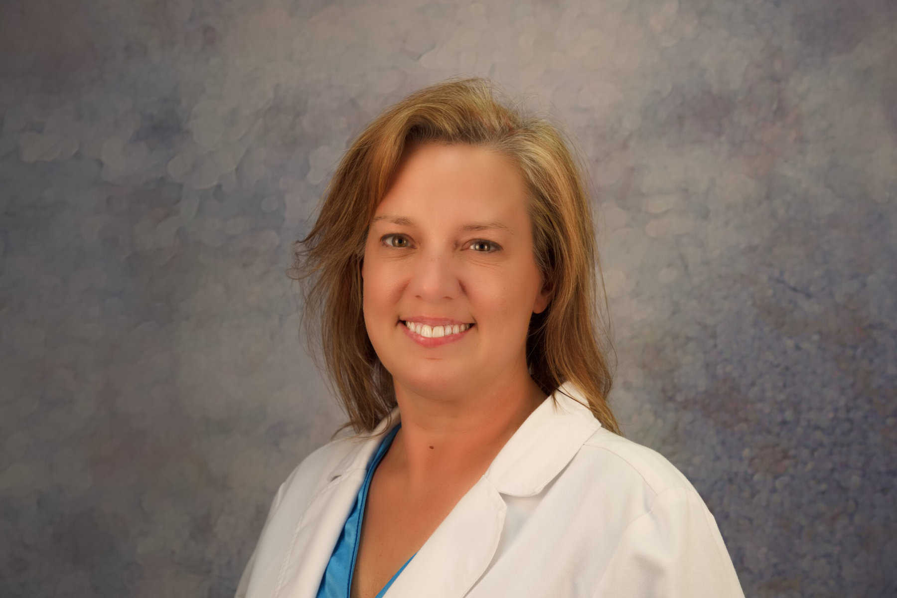 A woman in a lab coat smiling for the camera.