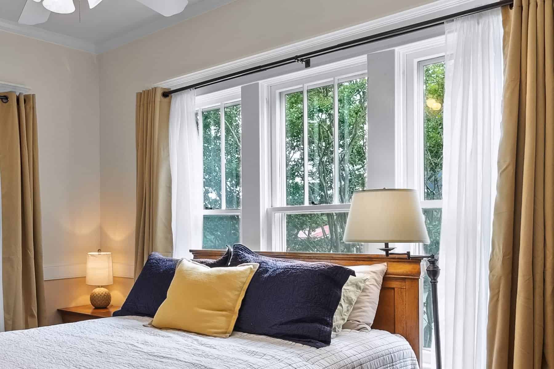 A bedroom with two windows and a ceiling fan.