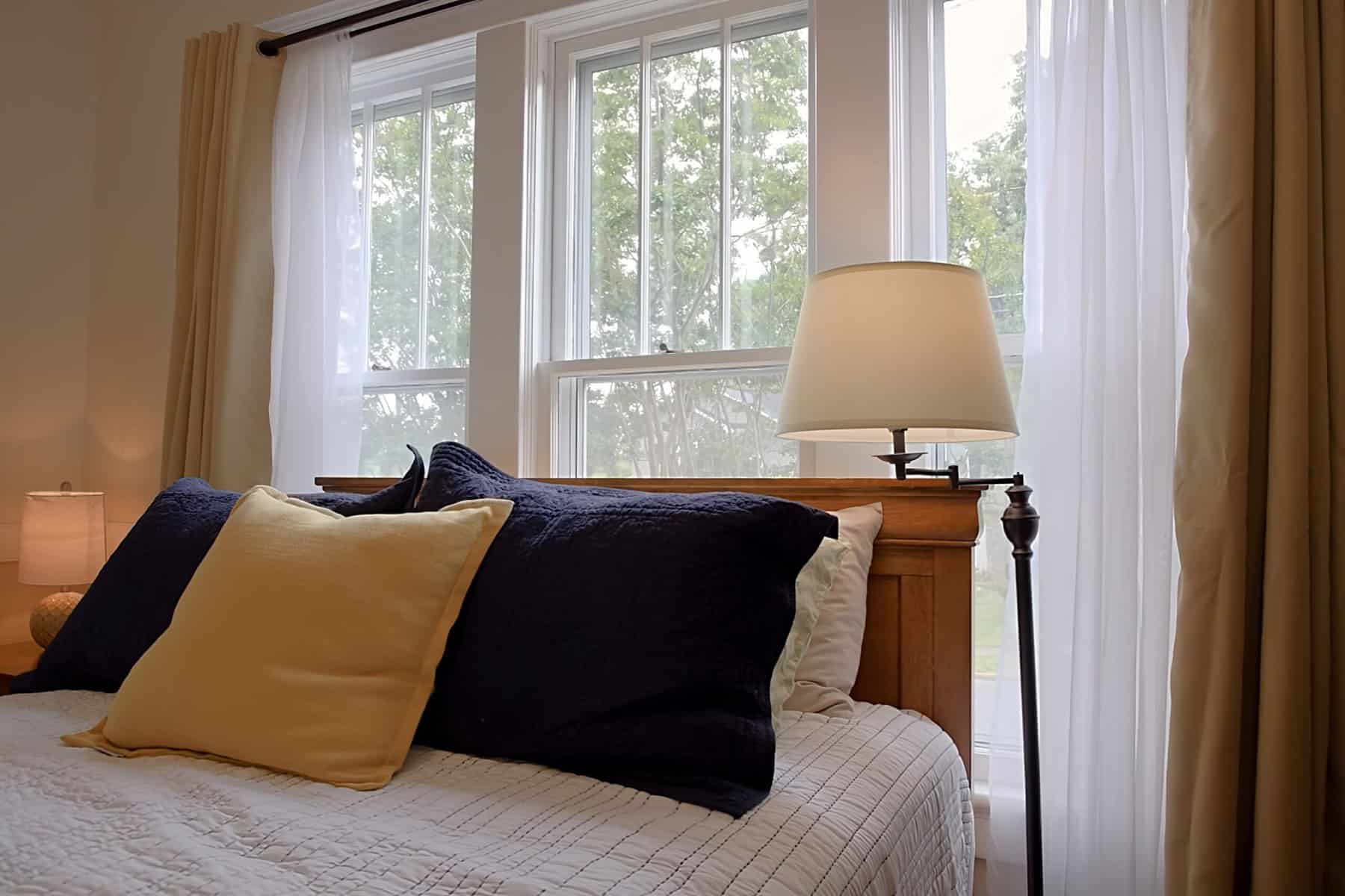 A bedroom with a bed and a lamp next to a window.