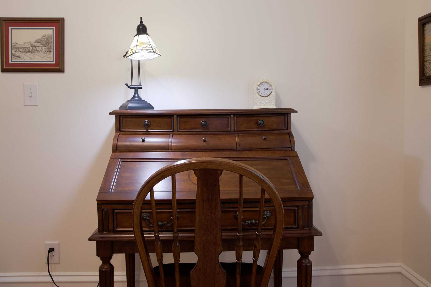 A desk with a lamp and a chair.